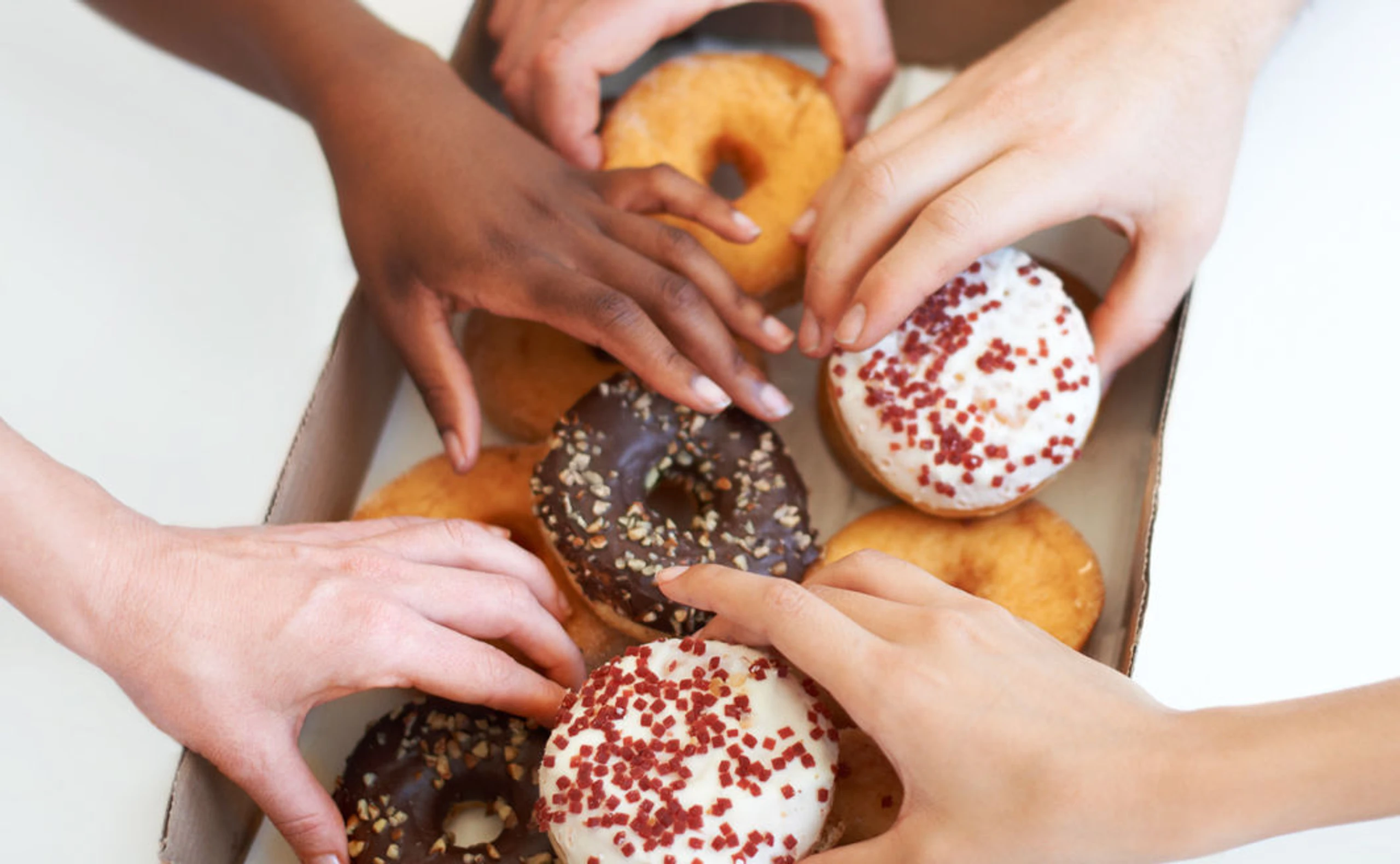 Frauenhände, die in eine Verpackung mit Donuts greifen