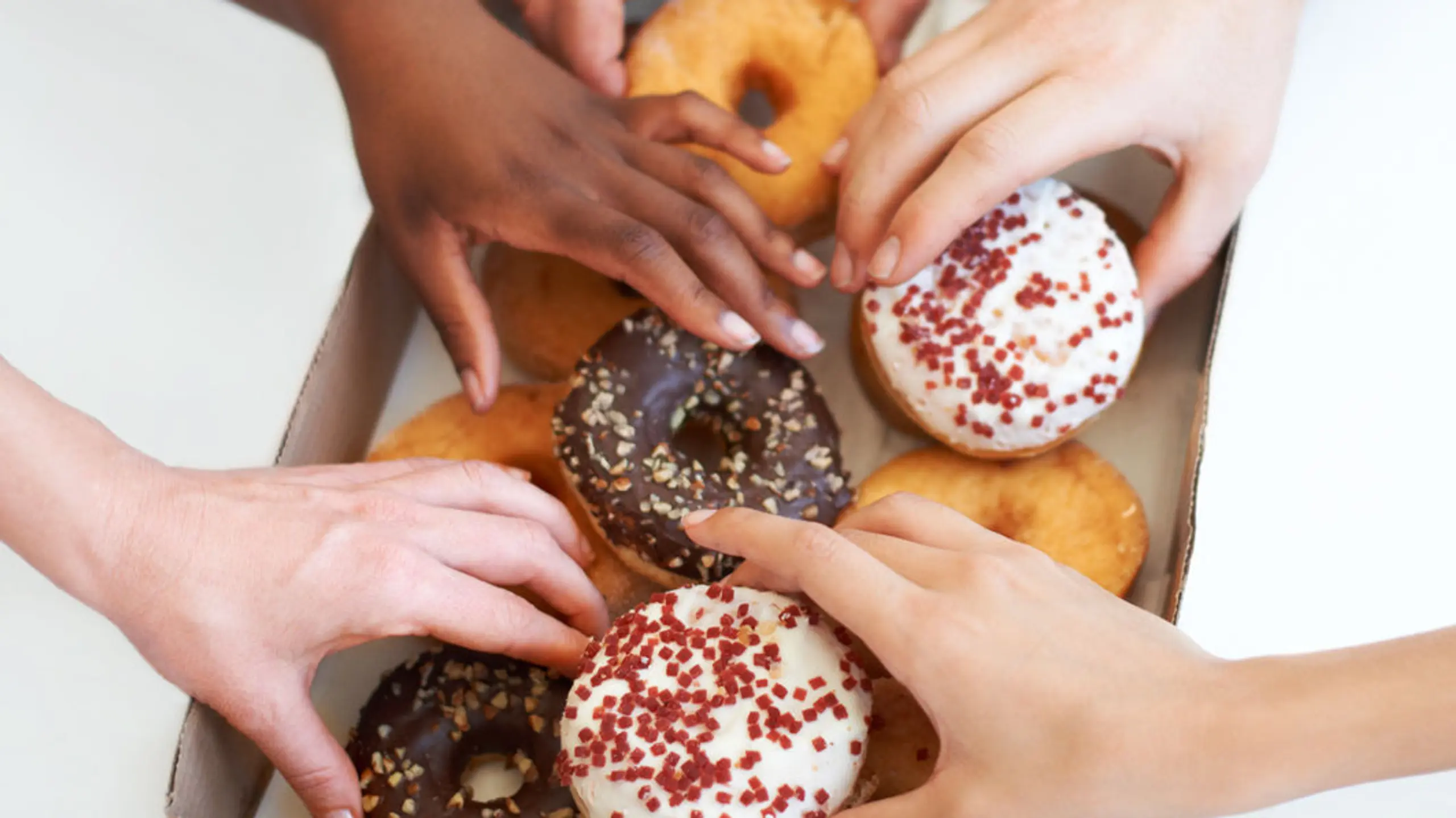 Frauenhände, die in eine Verpackung mit Donuts greifen