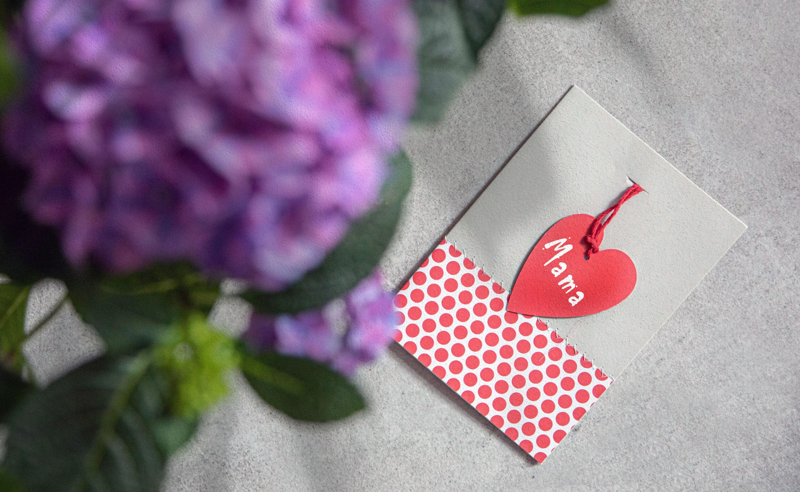 Muttertagskarte, die auf einem Tisch liegt. Im Vordergrund ist ein Blumenstrauß zu sehen.