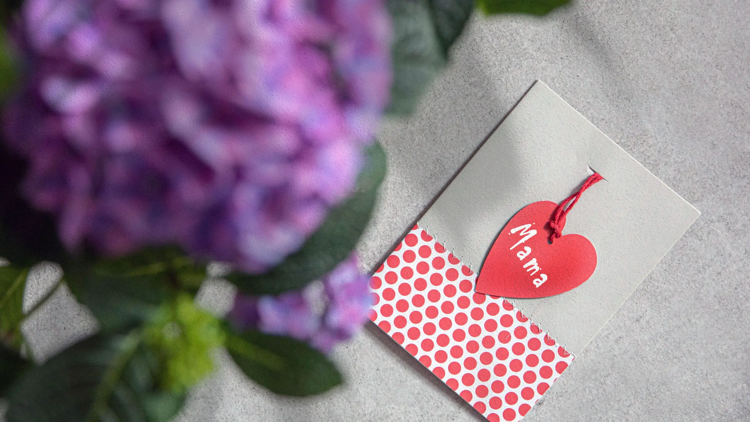 Muttertagskarte, die auf einem Tisch liegt. Im Vordergrund ist ein Blumenstrauß zu sehen.