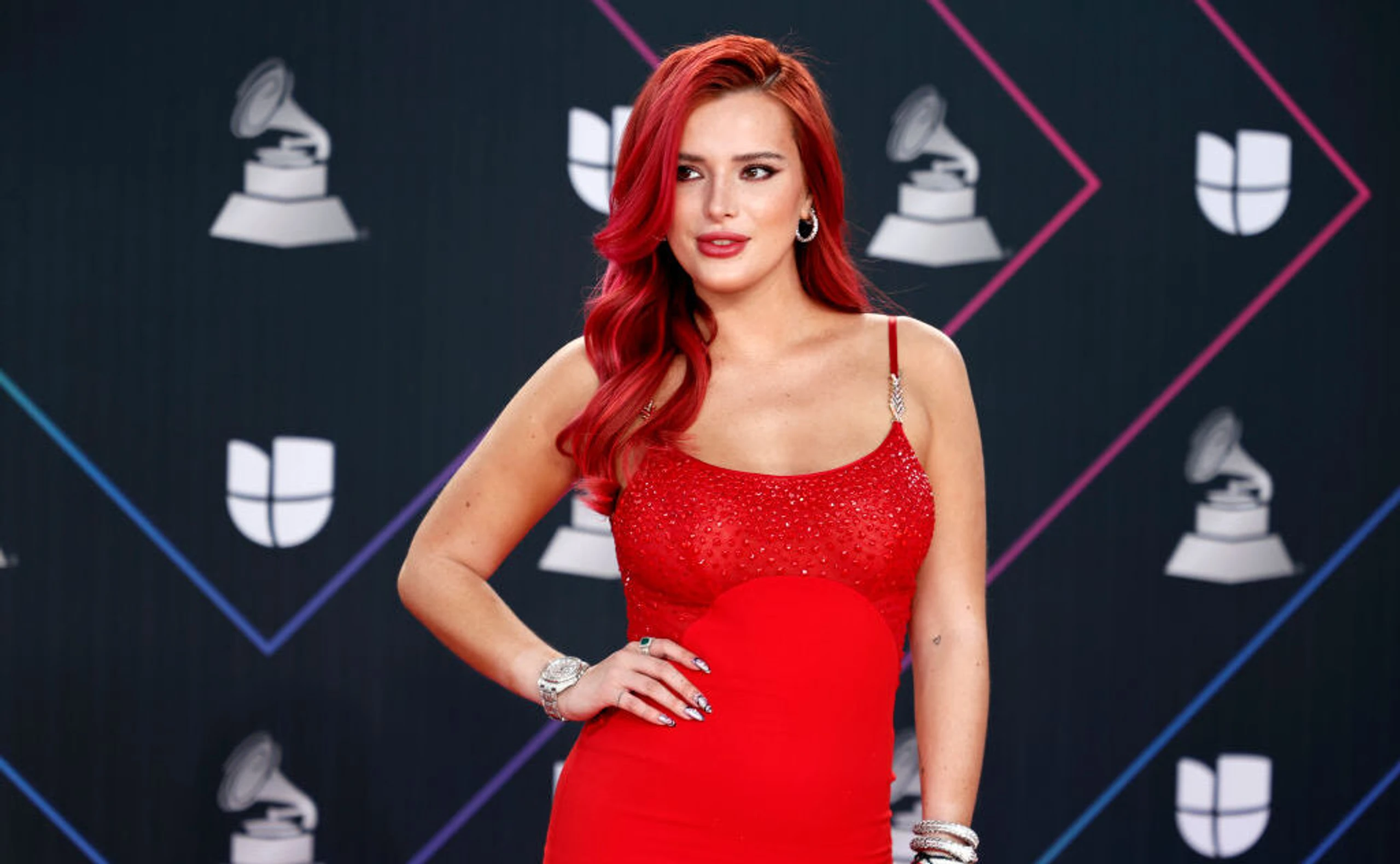Bella thorne befindet sich auf dem roten Teppich in einem roten Kleid.
