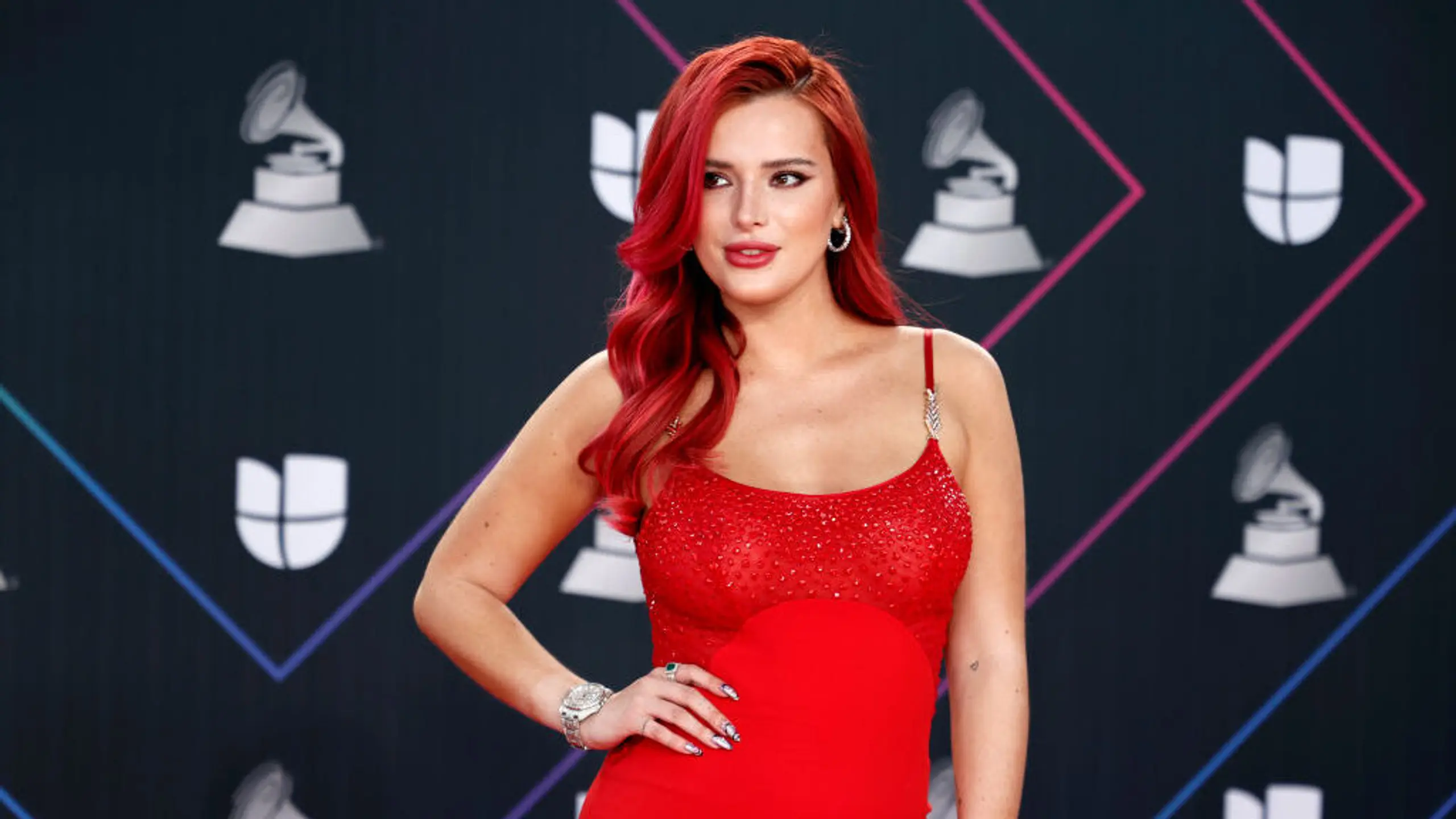 Bella thorne befindet sich auf dem roten Teppich in einem roten Kleid.