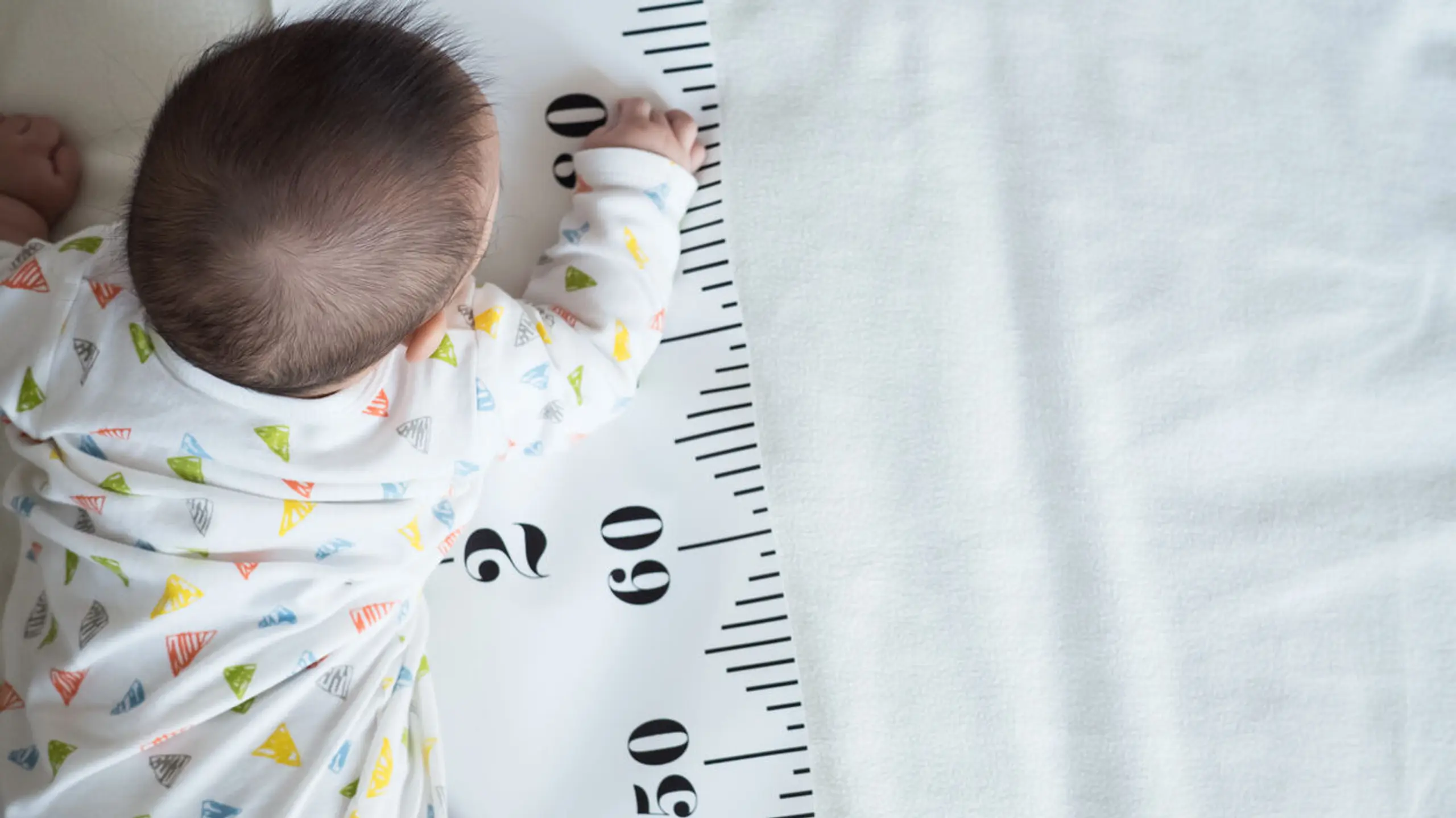 Baby mit einem Maßband unterm Körper
