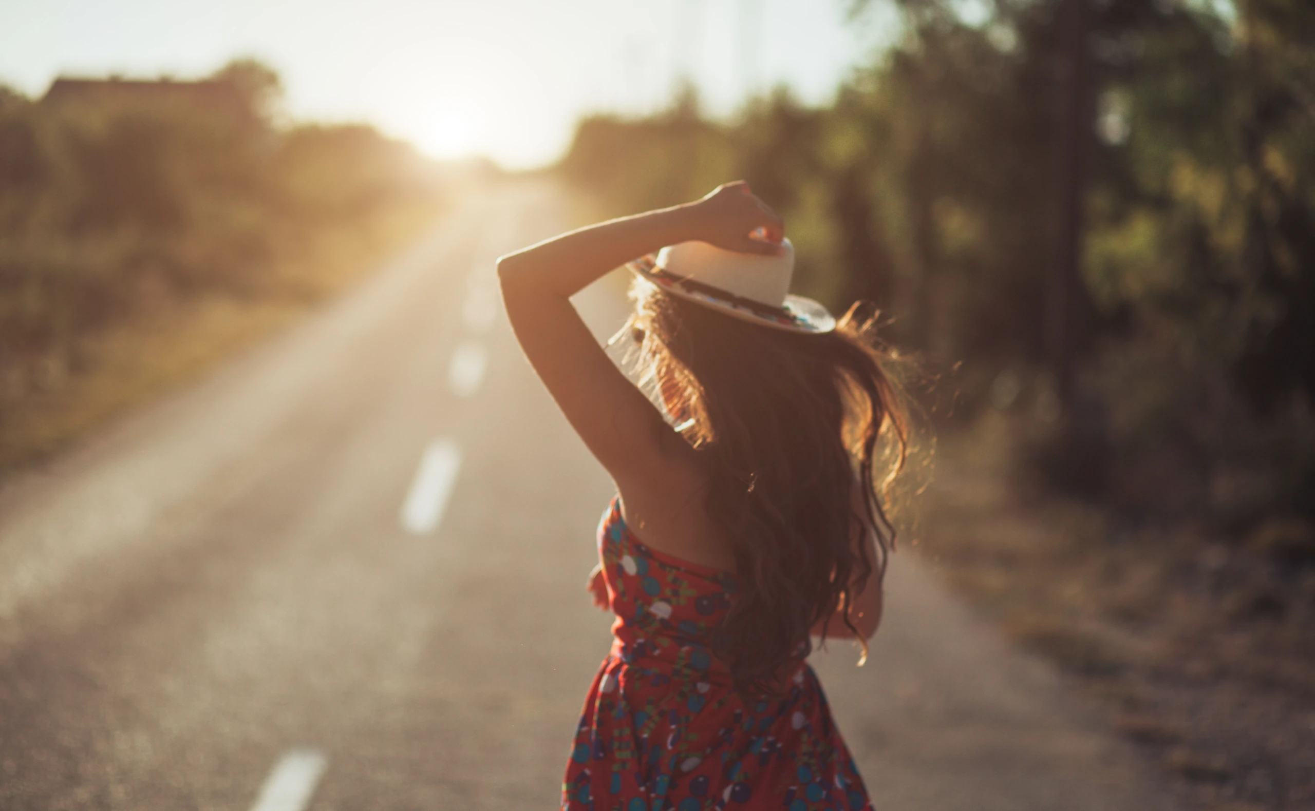 eine Frau mit Hut und einem Boho-Kleid in der Natur am tanzen.