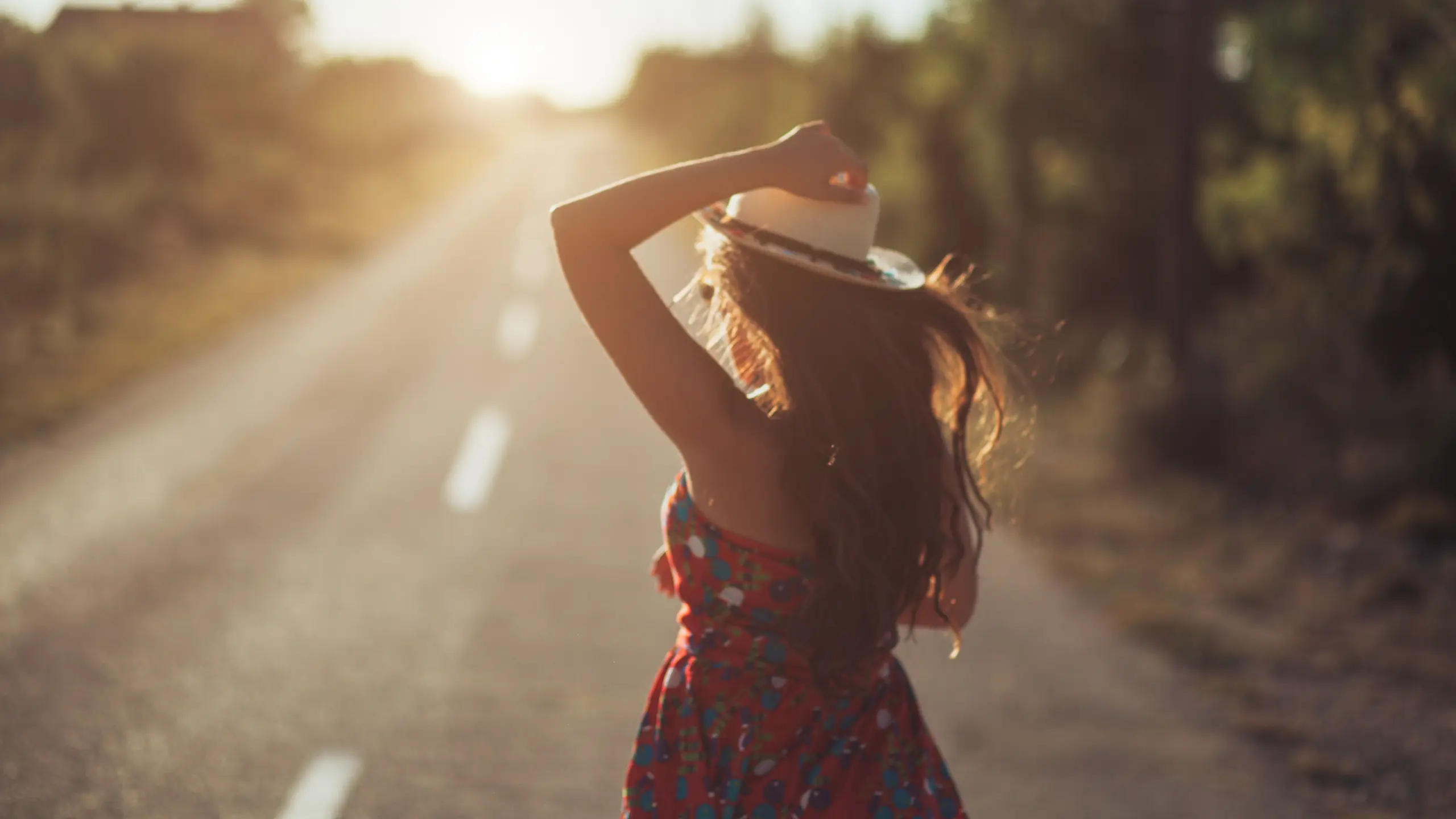 eine Frau mit Hut und einem Boho-Kleid in der Natur am tanzen.