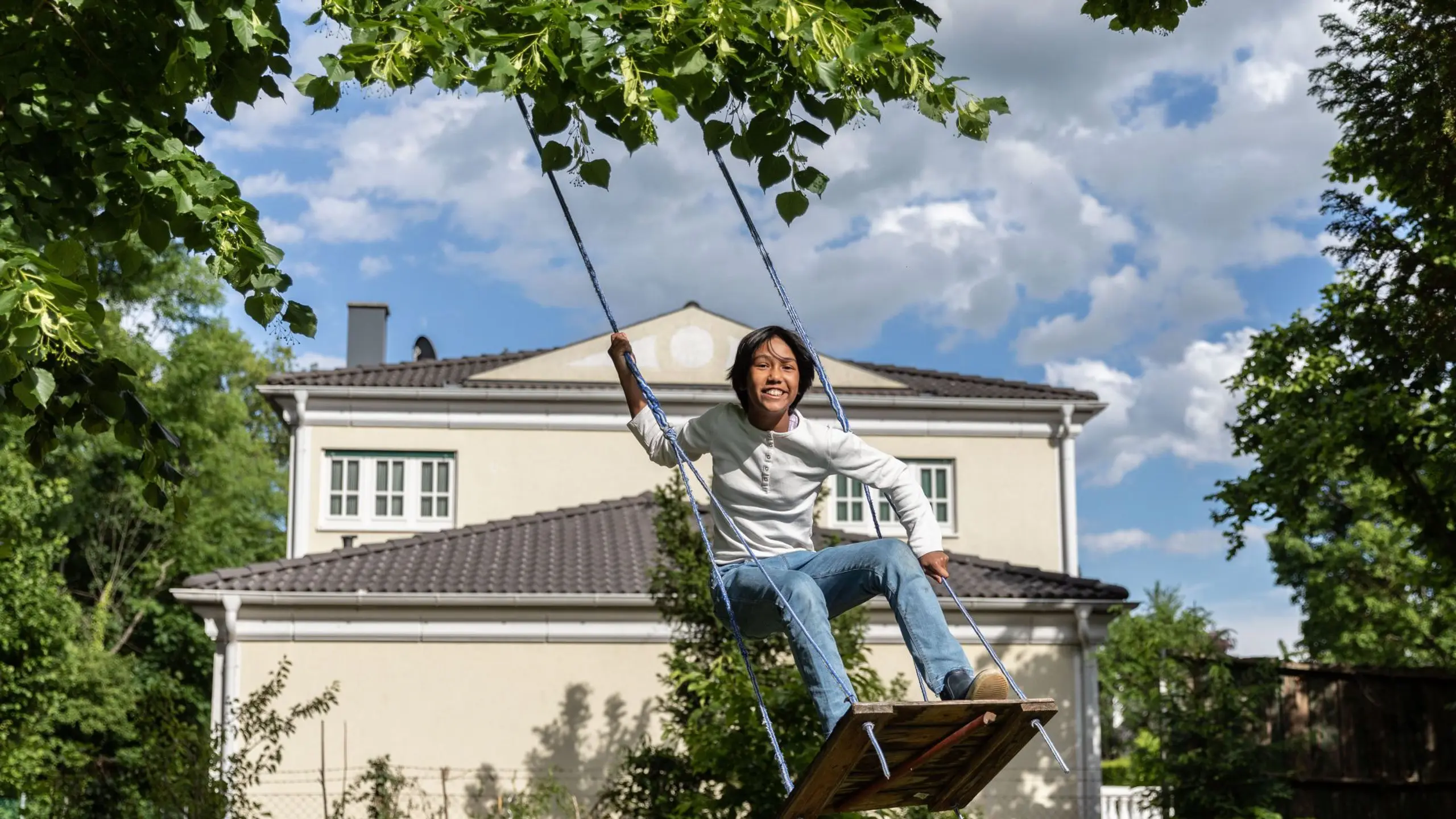 Ein glückliches Kind steht auf der Schaukel und freut sich