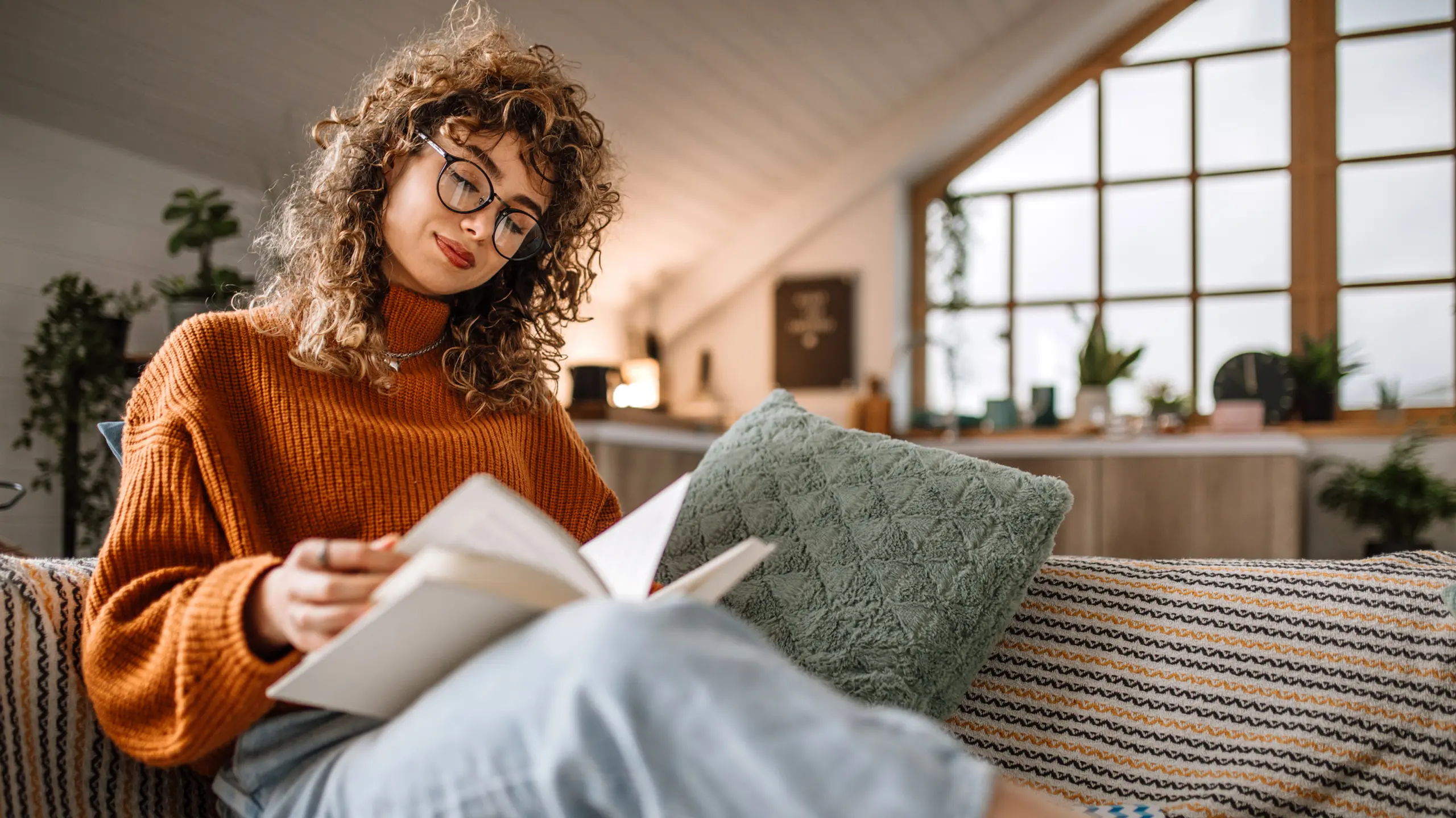 Frau, die auf einer kuscheligen Couch sitzt und ein Buch liest