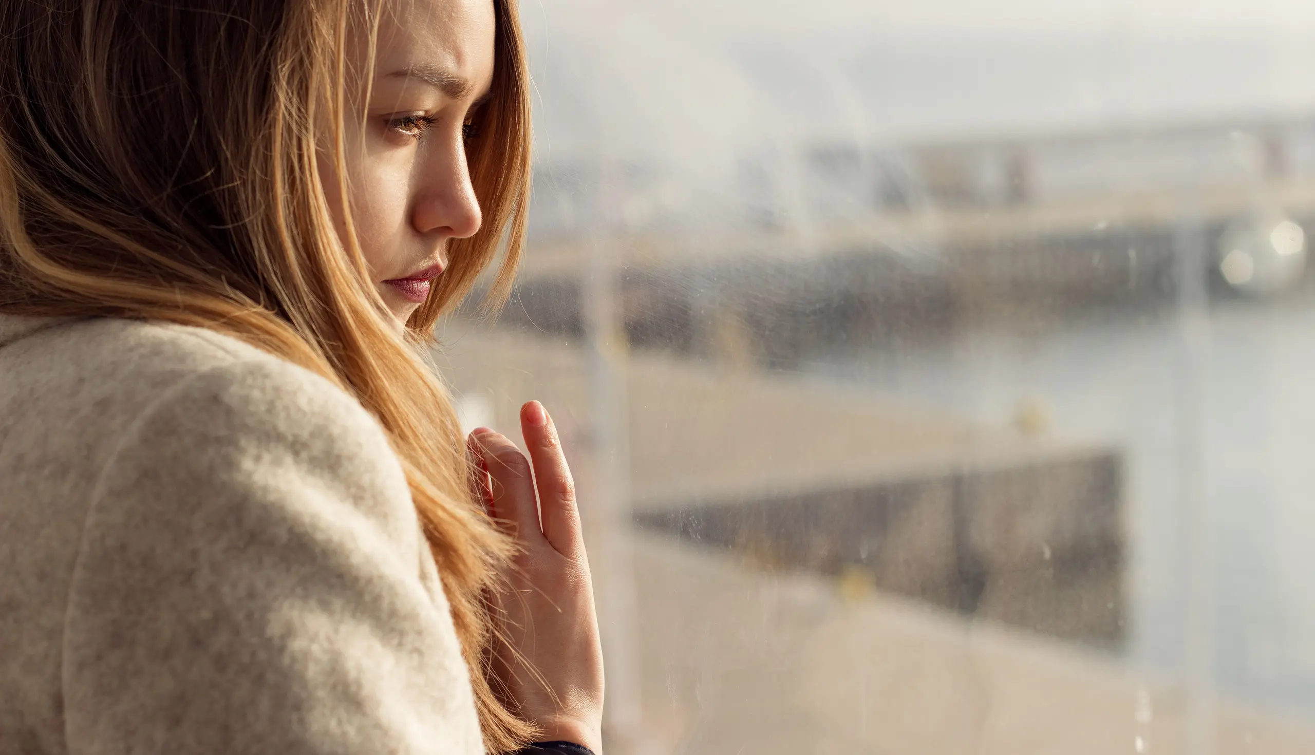 Traurige Frau blickt aus dem Fenster