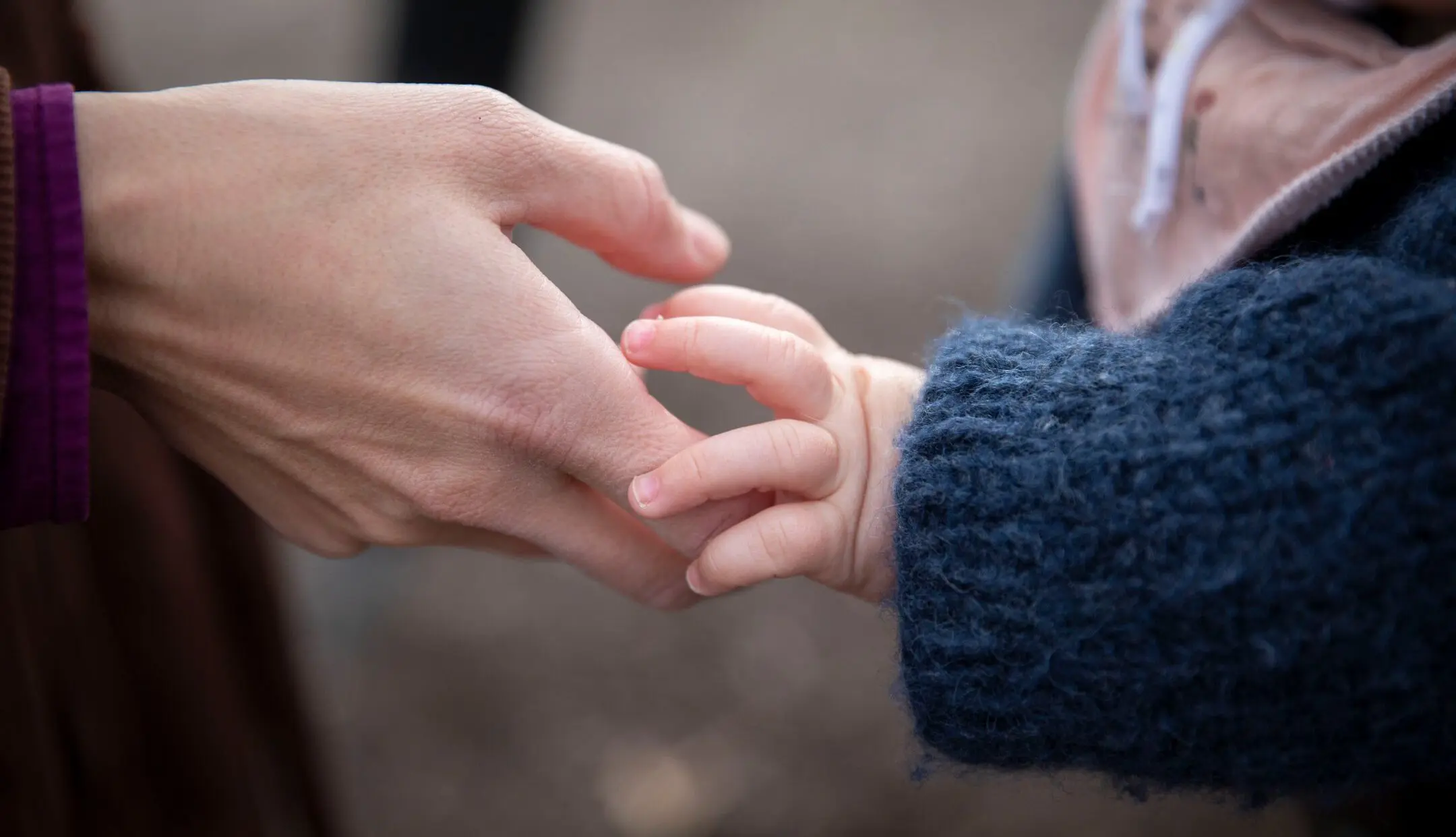 Ein Kind hält die Hand eines Elternteils.