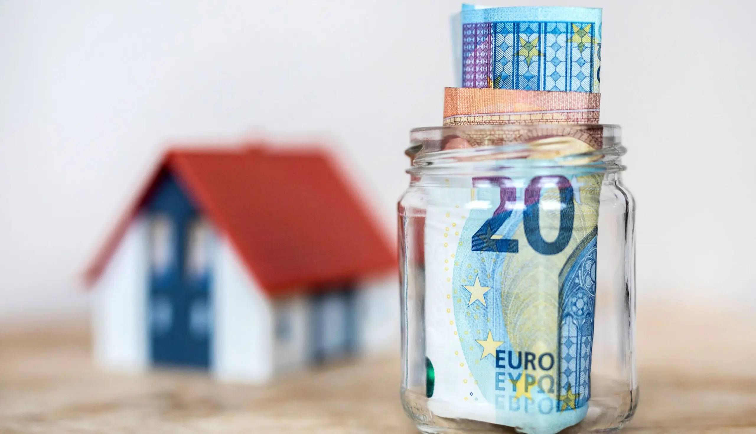 Bausparen ist in Österreich beliebt: Haus und Glas mit Geld