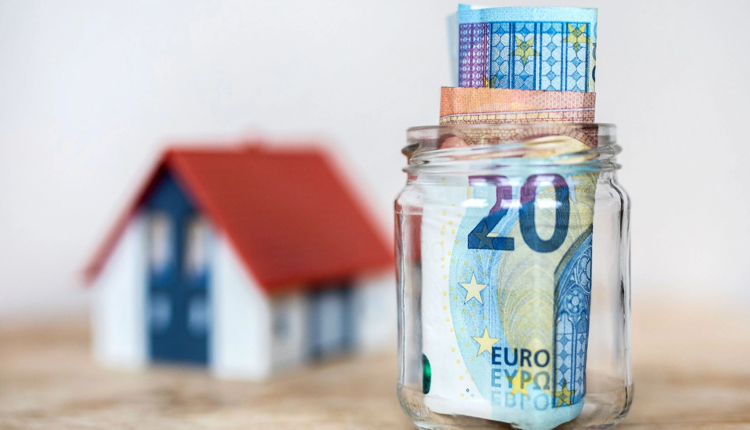 Bausparen ist in Österreich beliebt: Haus und Glas mit Geld