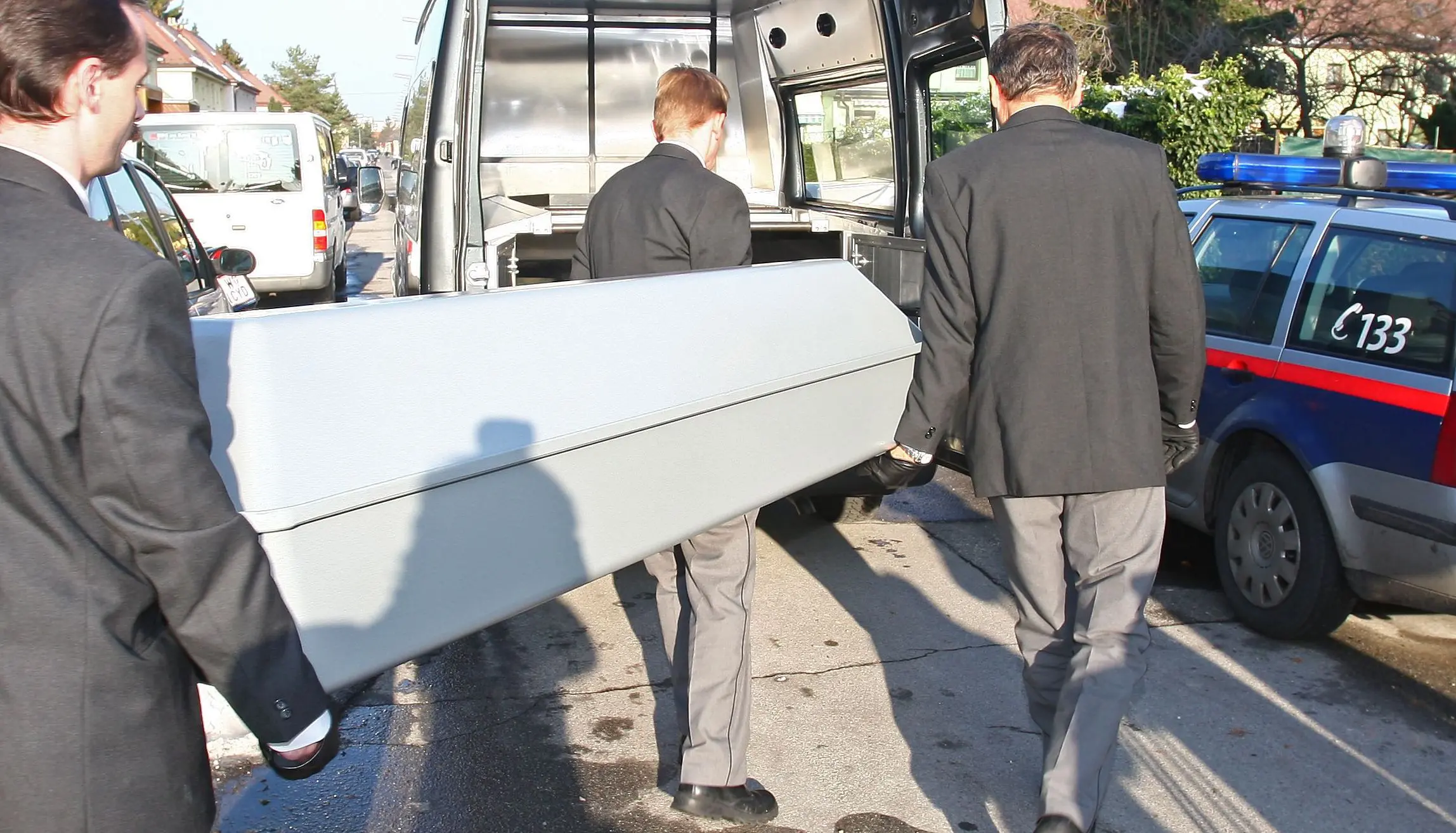 Symbolfoto: Ein Sarg wird in den Leichenwagen getragen.