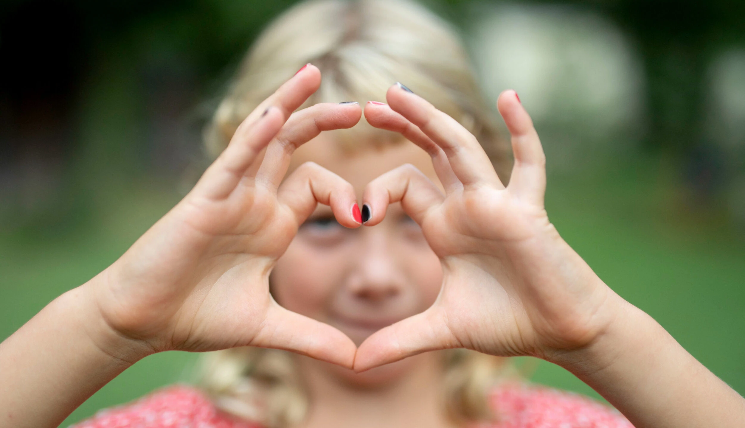 Selbstliebe: Ein Kind formt mit der Hand ein Herz