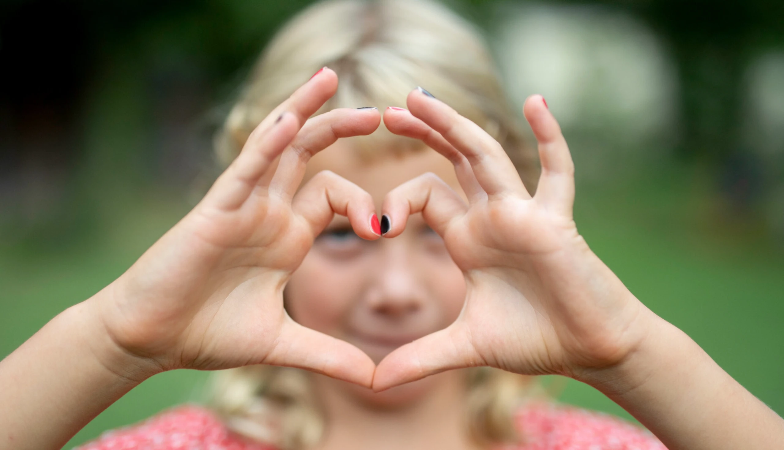 Selbstliebe: Ein Kind formt mit der Hand ein Herz