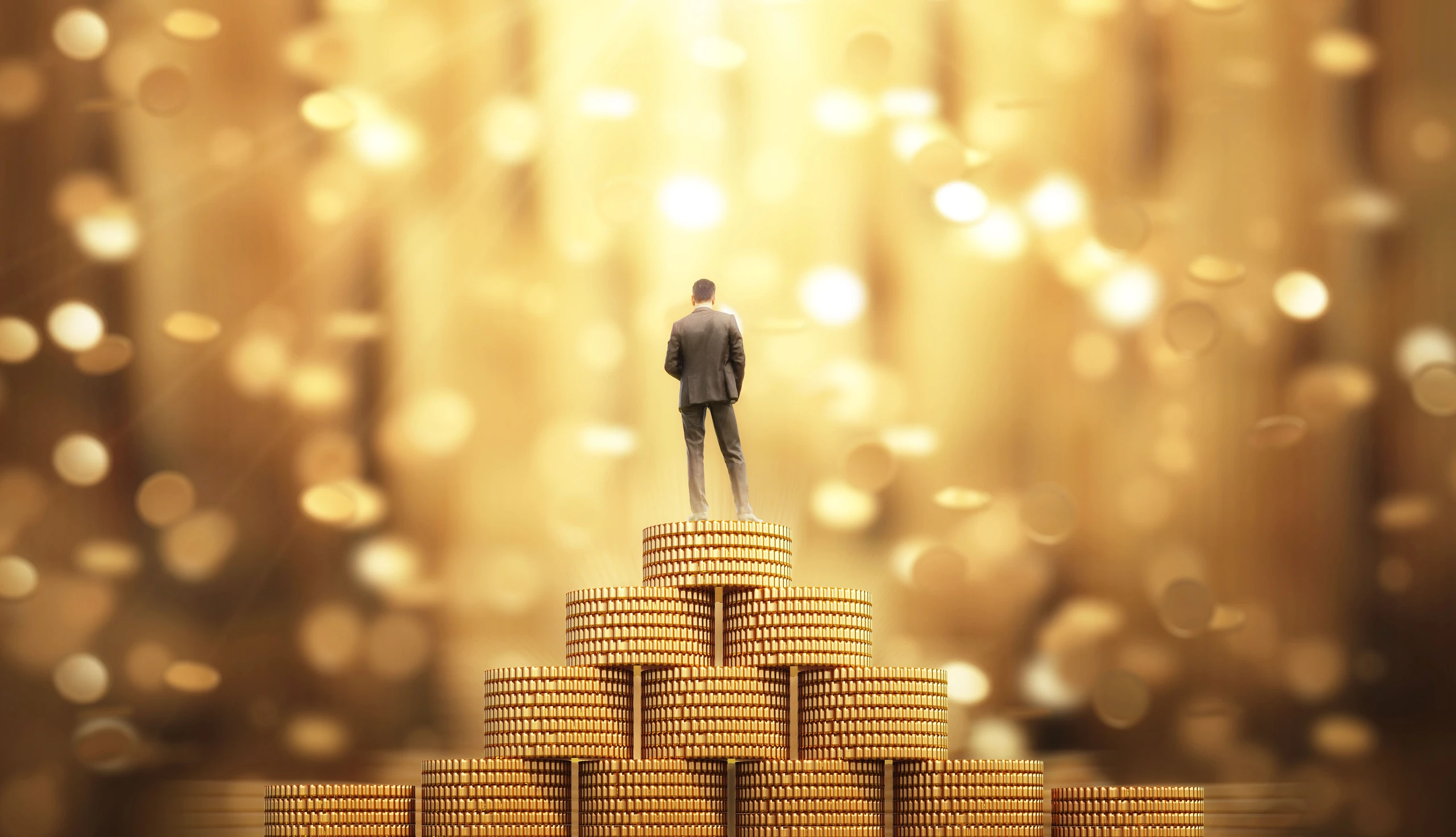 Vermögenssteuer: Mann steht auf Goldmünzen