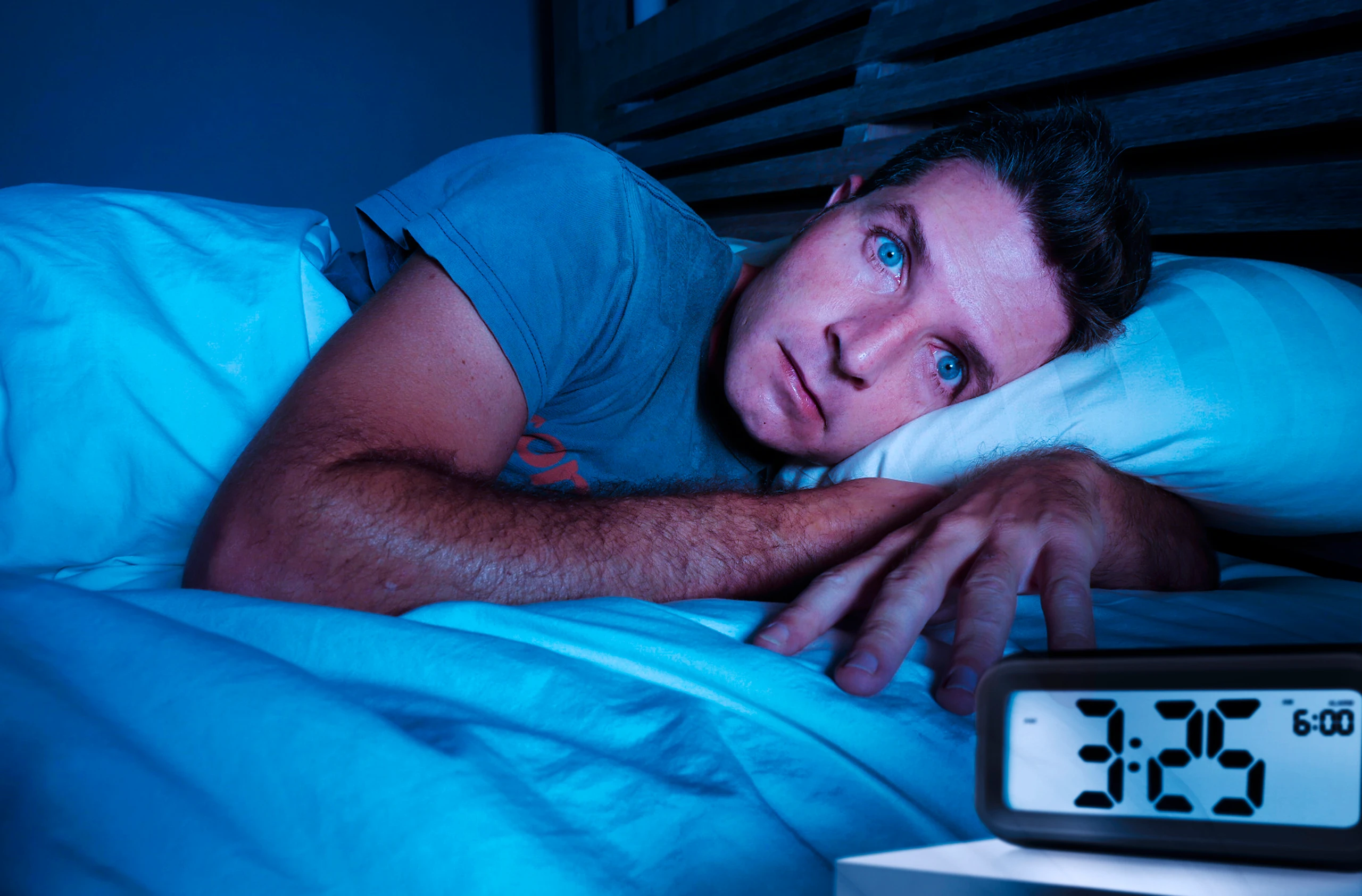Mann liegt mit geöffneten Augen im Bett