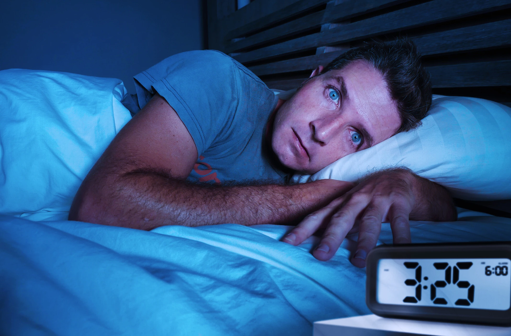 Mann liegt mit geöffneten Augen im Bett