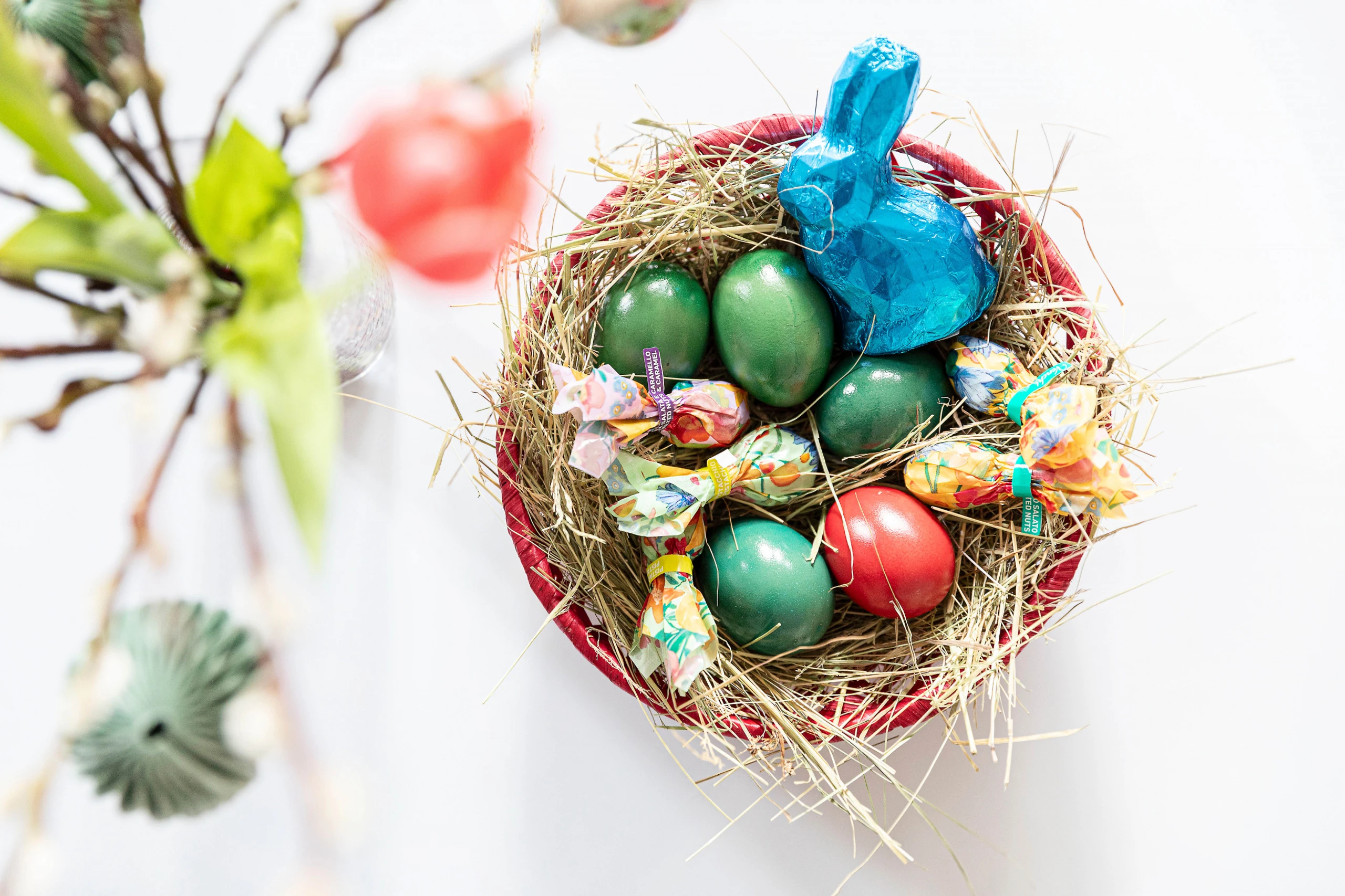 Osternest, das mit bunten Ostereiern und Süßigkeiten gefüllt ist