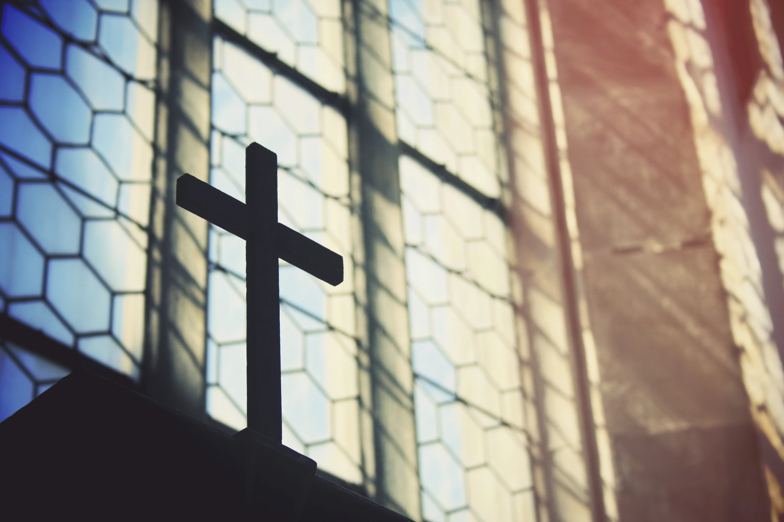 Ein Kreuz in einer Kirche vor einem Fenster.