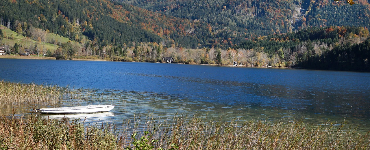 Ruhiger See mit Boot, Herbstlandschaft, Berge im Hintergrund. FOTO © WEINFRANZ (lt. UrhG)