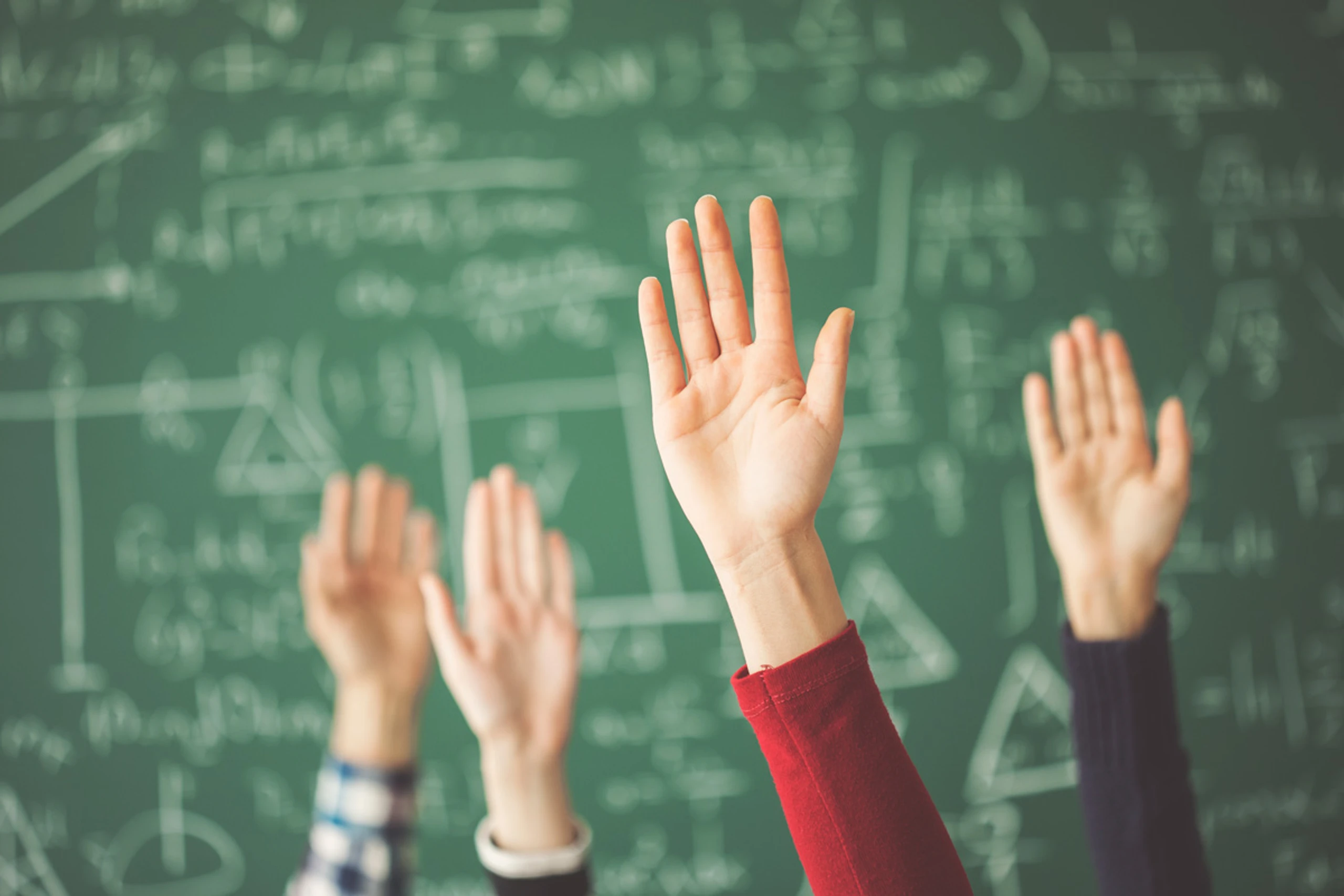 Schüler:innen zeigen in der Schule auf.