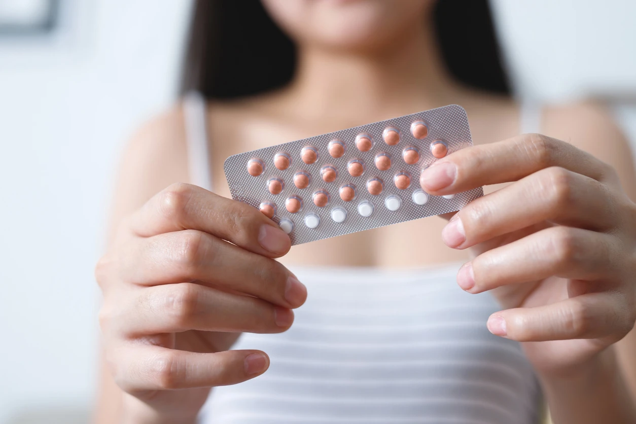 Eine Frau hält eine Packung eine Anti-Baby-Pille in der Hand.