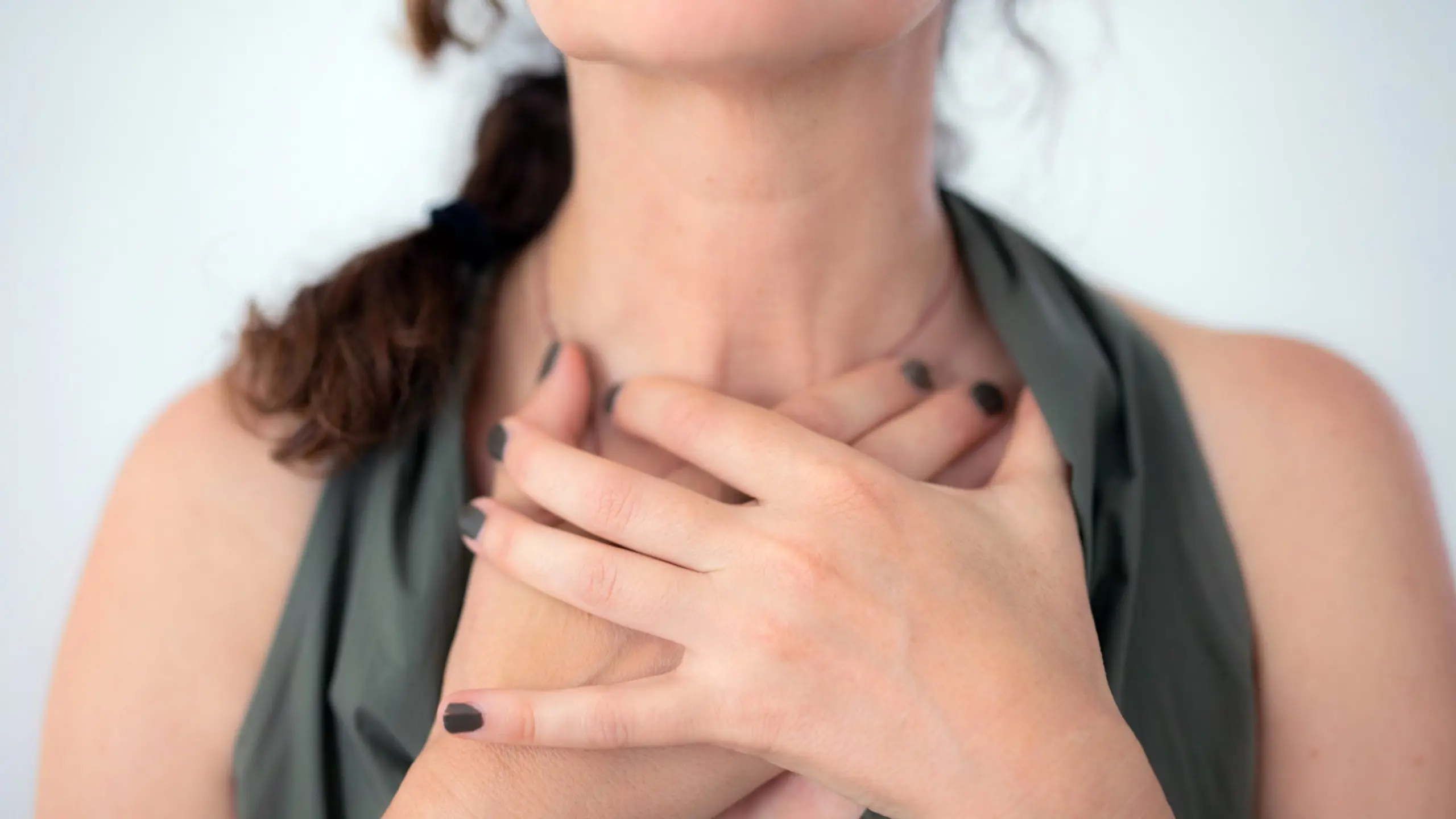 Frau, die sich mit beiden Händen an den Hals greift