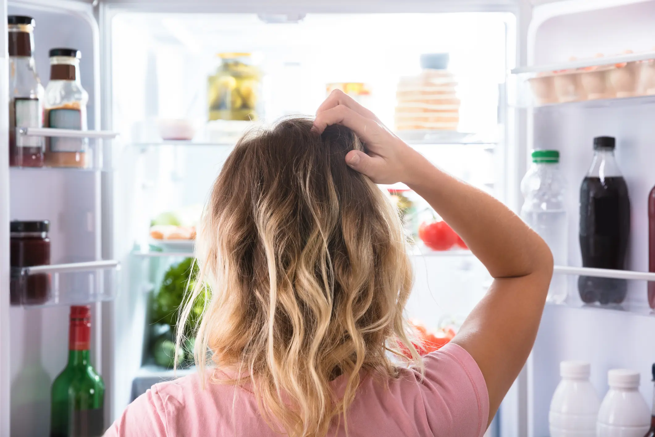 Frau vor geöffnetem Kühlschrank