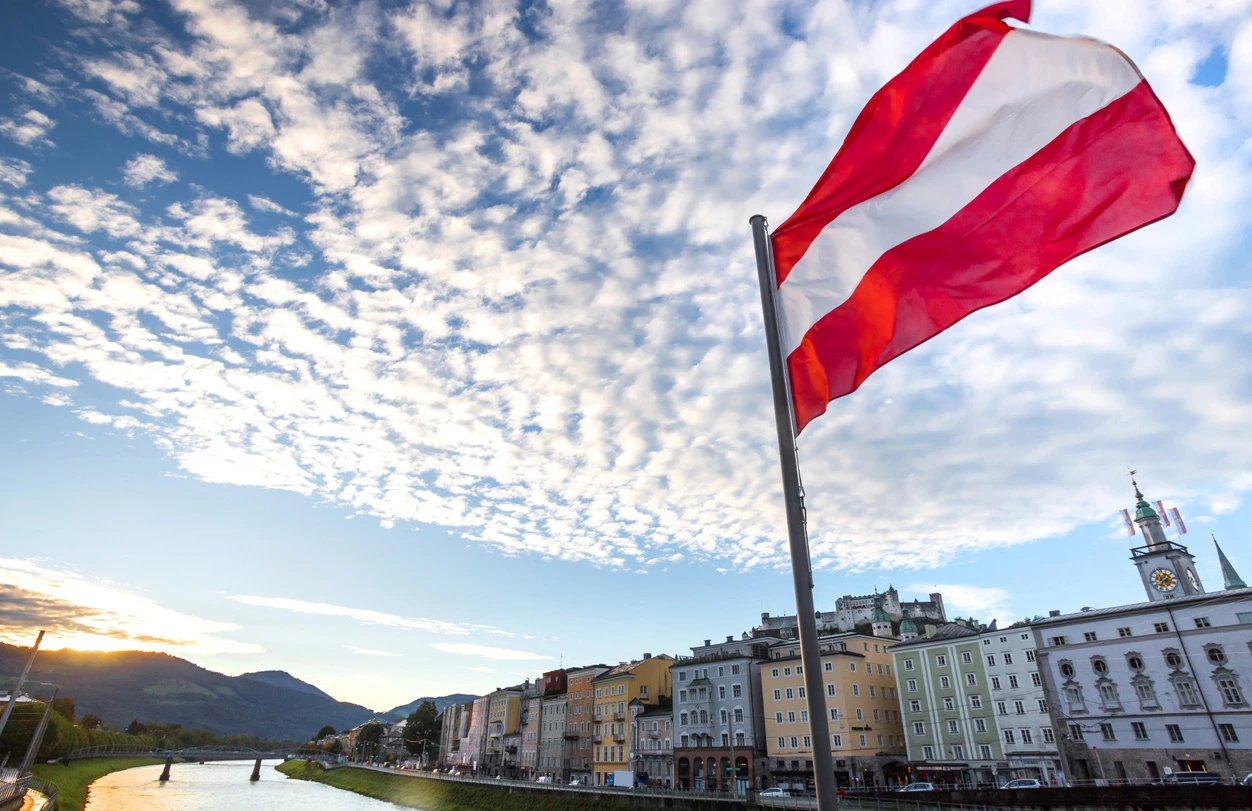 Eine österreichische Fahne weht über historischem Salzburger Stadtbild.