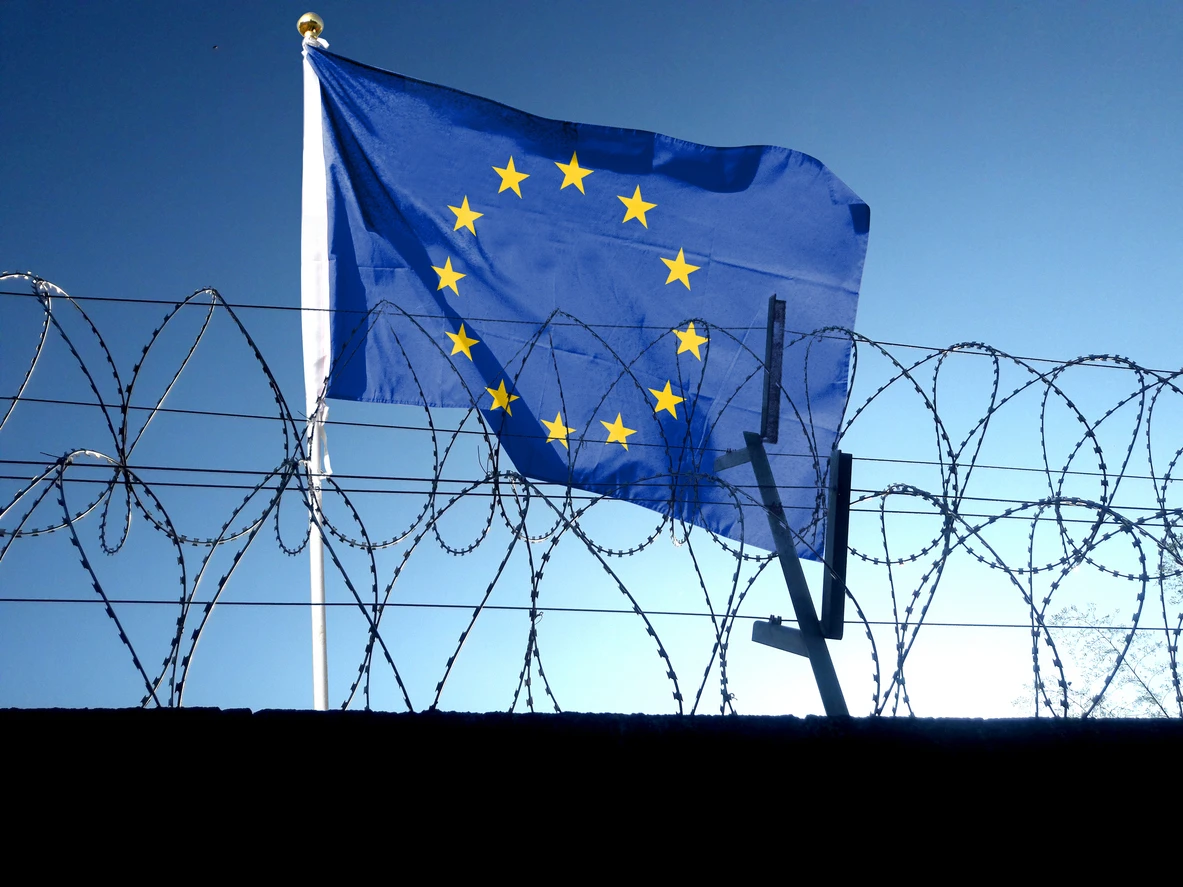Ein Flagge der EU weht nahe eines Grenzzaunes.