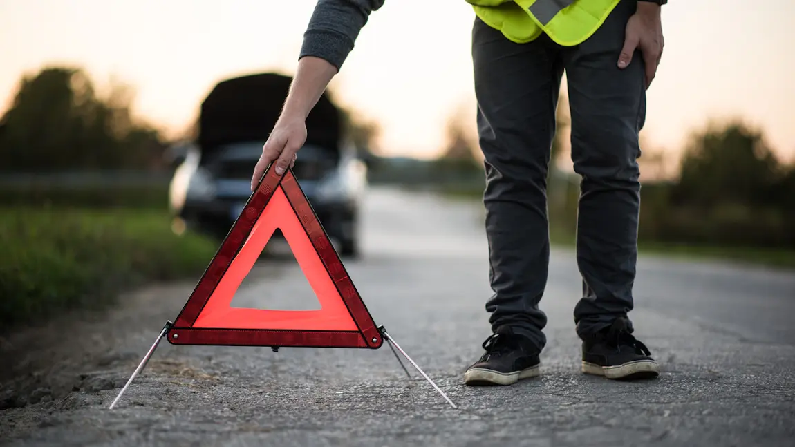 Autofahrer stellt das Pannendreieck am Straßenrand auf.