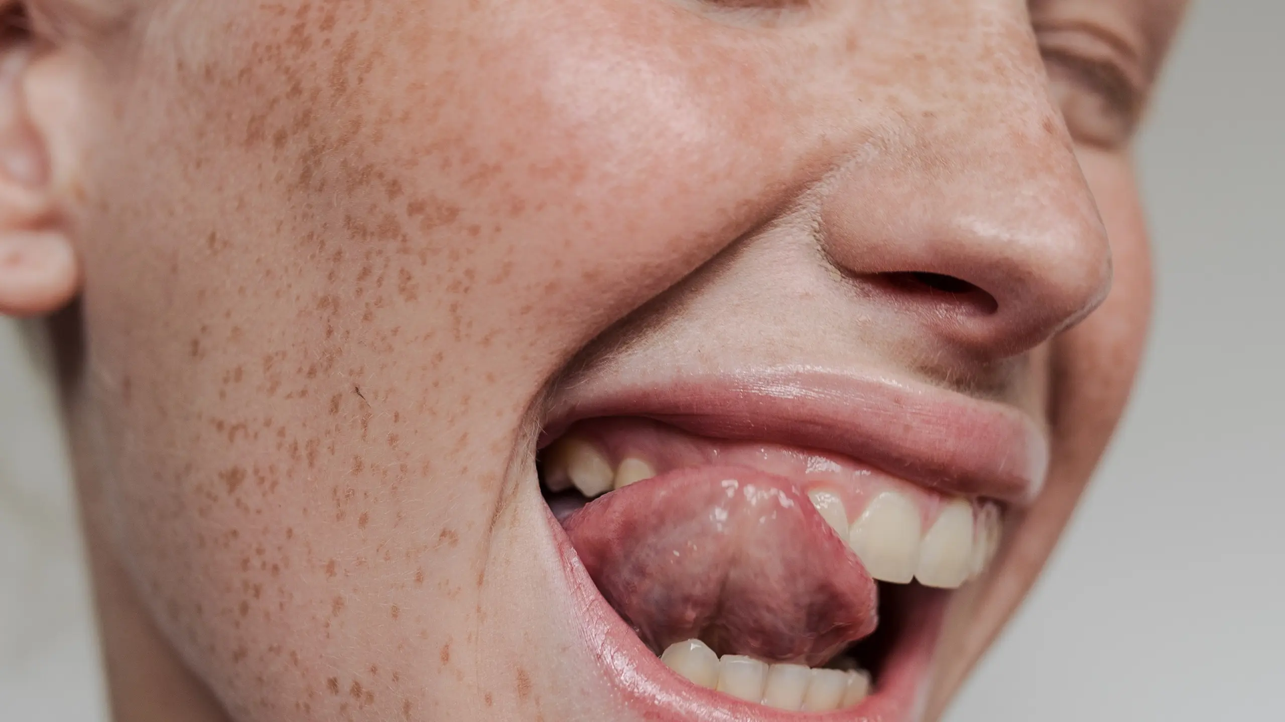 Frau, die sich mit Zunge über Zähne schleckt