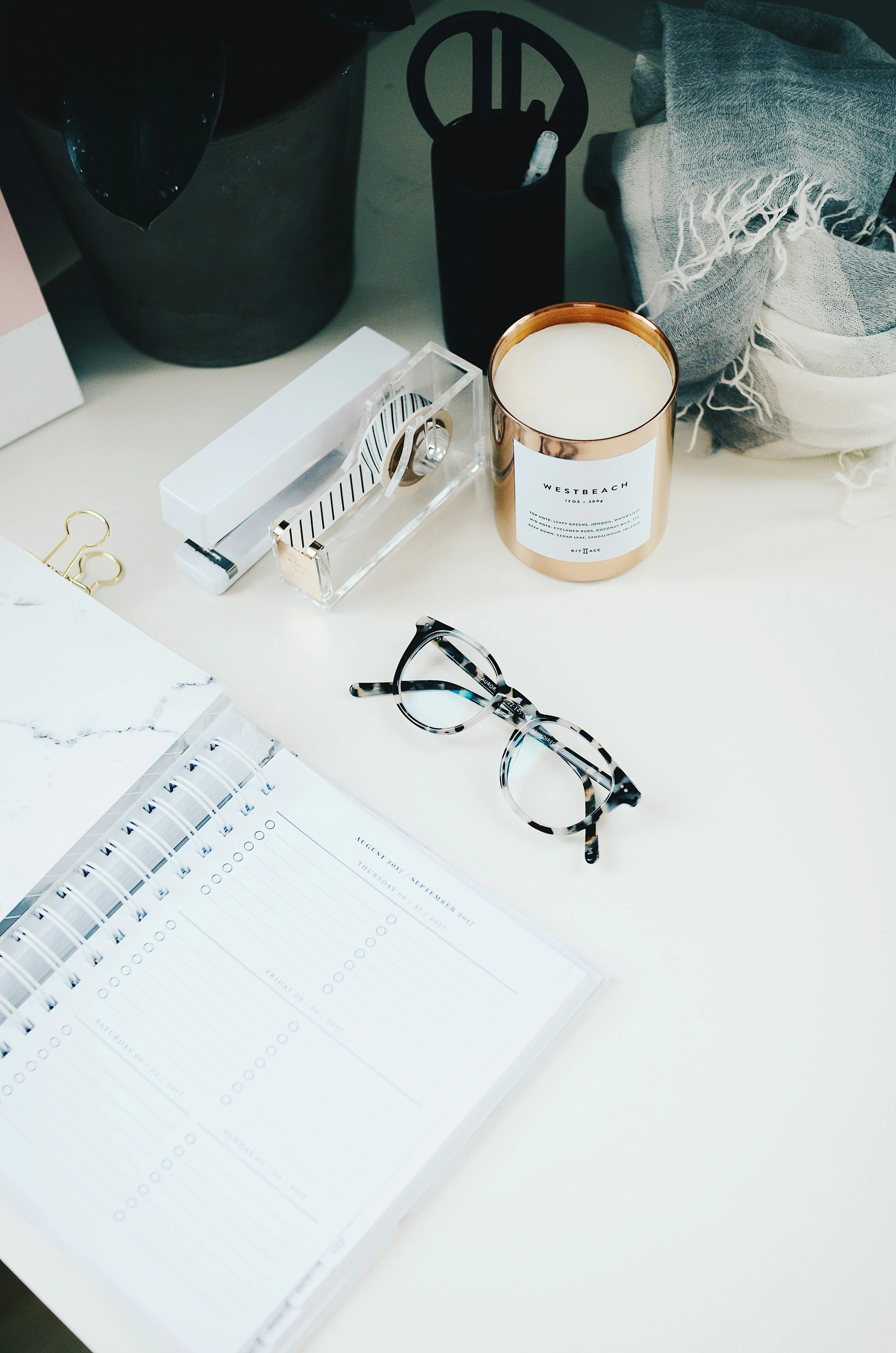 Schreibtisch mit Planer, Kerze und Brille