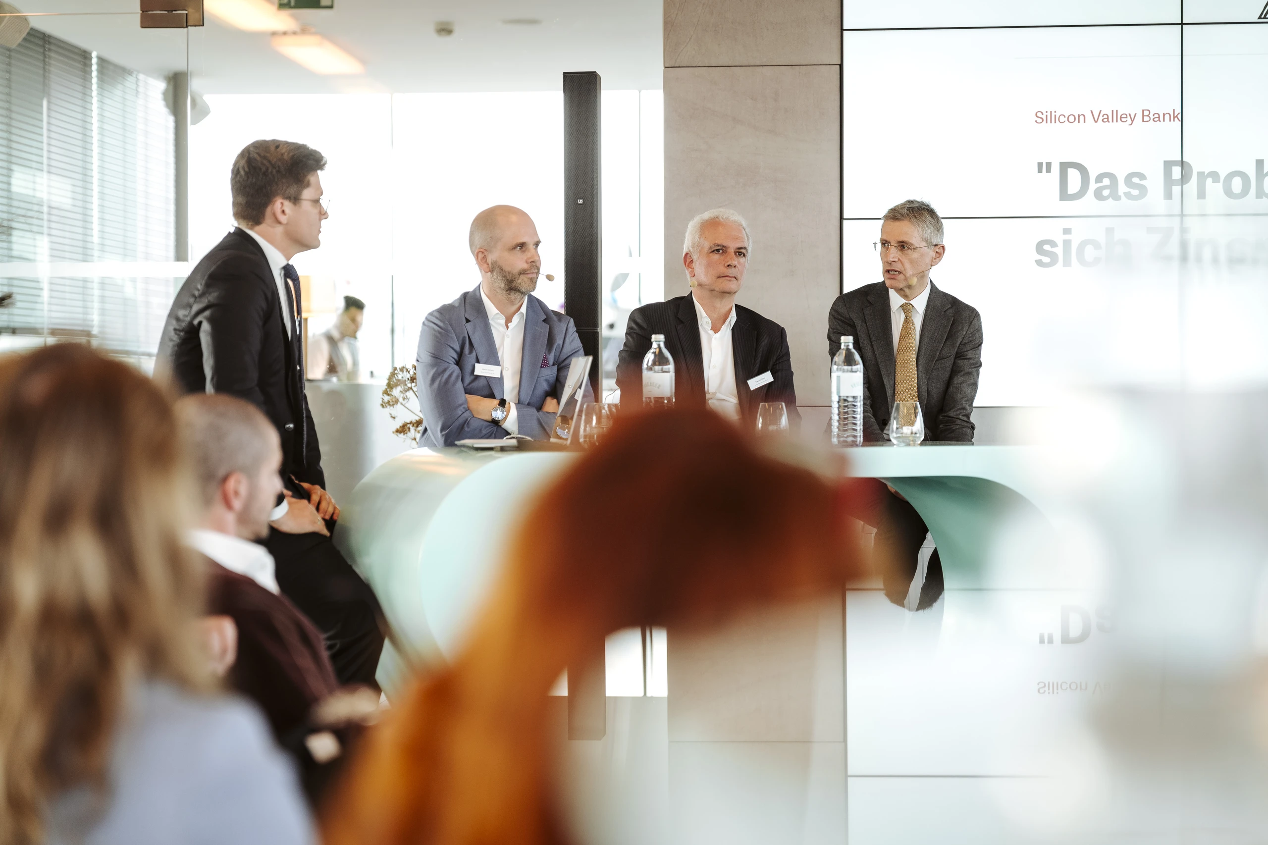 Vier Männer bei einer Podiumsdiskussion mit Silicon Valley Bank Logo im Hintergrund. Foto von Nadine Studeny.