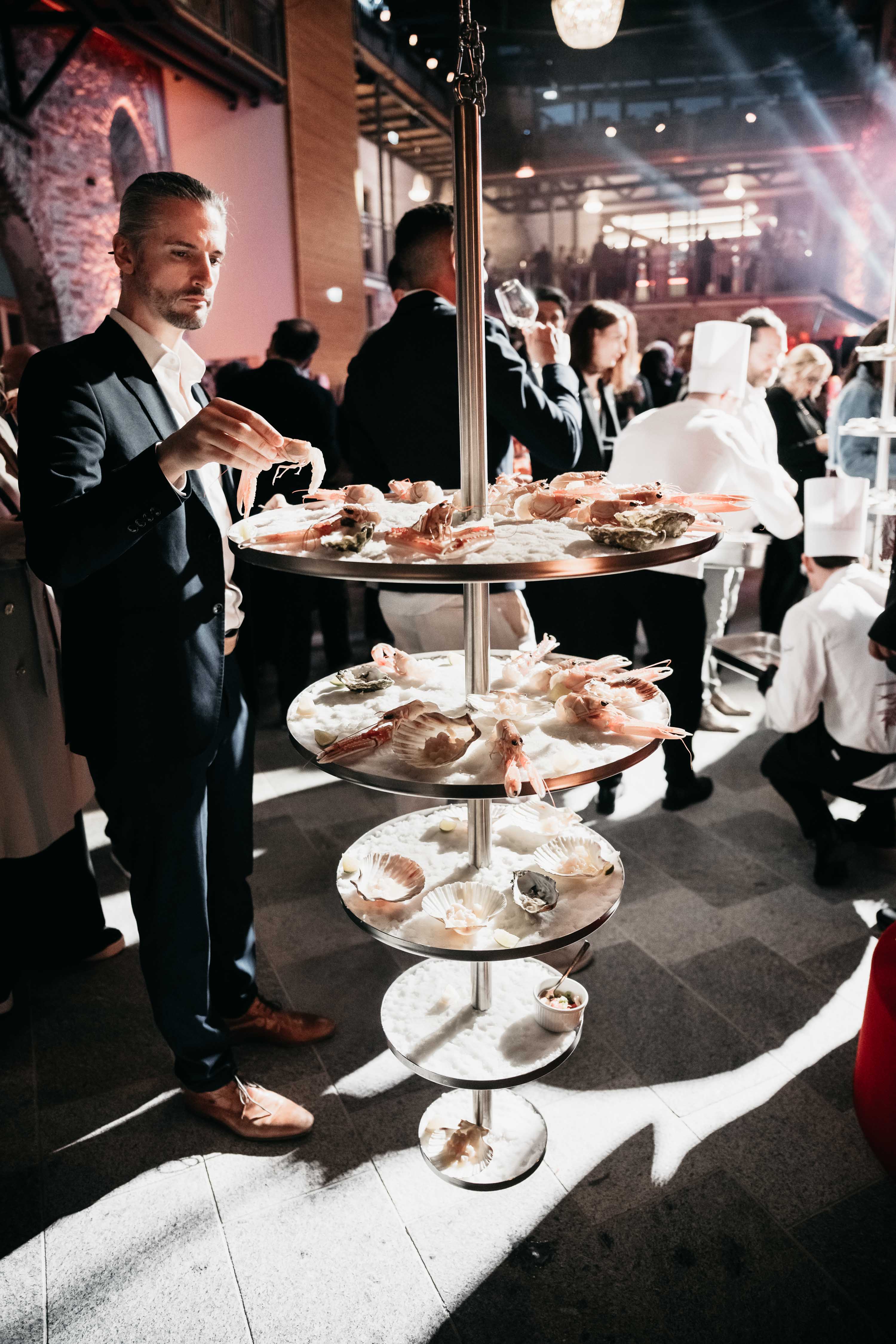 Mann präsentiert Meeresfrüchte auf Eisschalen. Foto von MATIC KREMZAR.