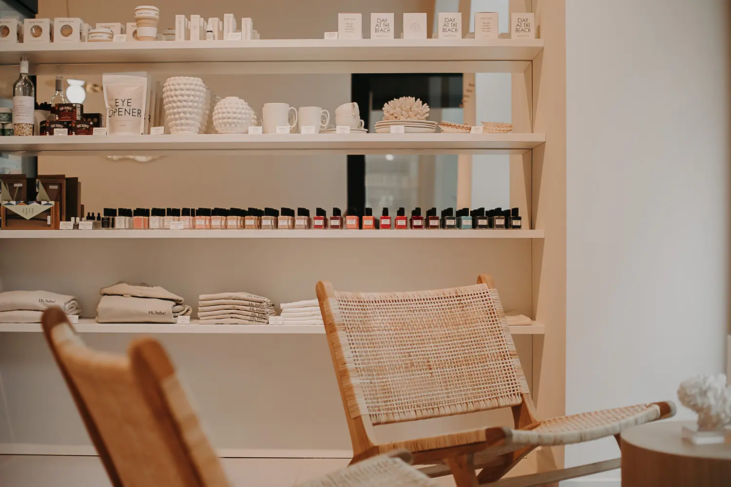 Nagelstudio, im Vordergrund geschmackvolle Stühle und im Hintergrund ein Regal mit Produkten