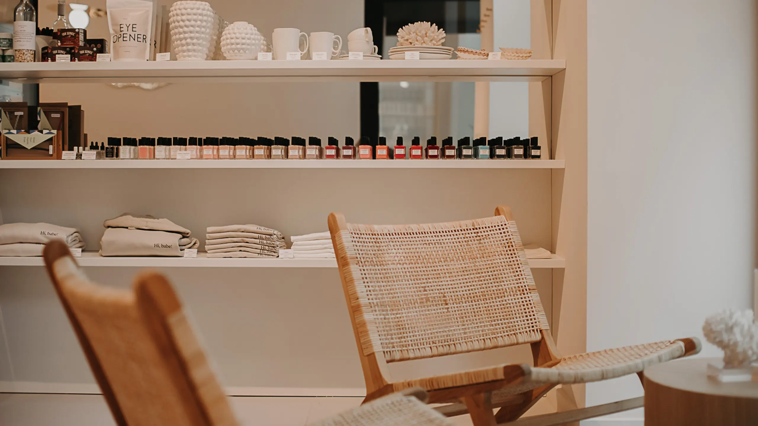 Nagelstudio, im Vordergrund geschmackvolle Stühle und im Hintergrund ein Regal mit Produkten