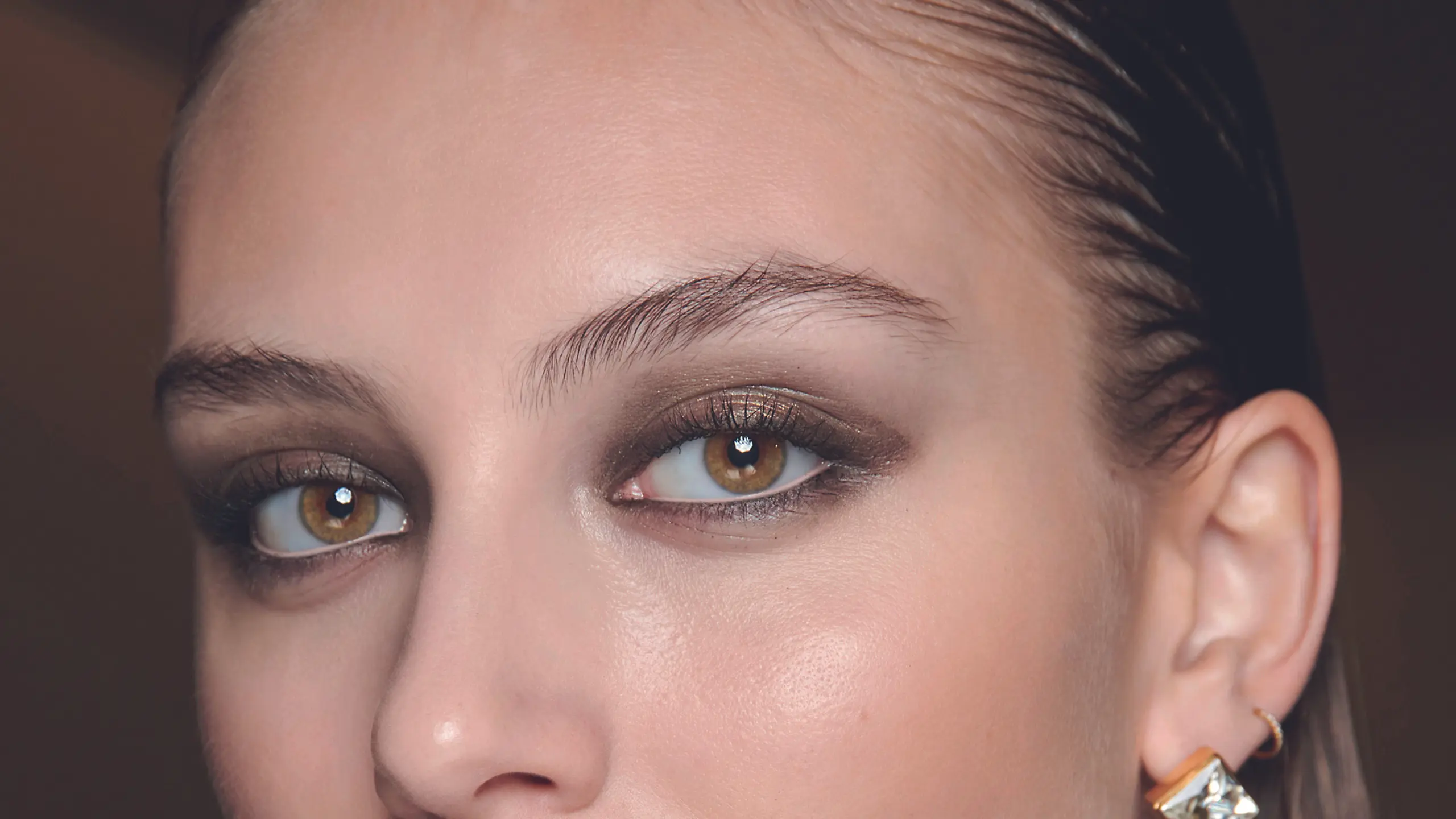 Model BTS mit brauen schimmernden Smokey-Eyes und zurückgegelte Haare