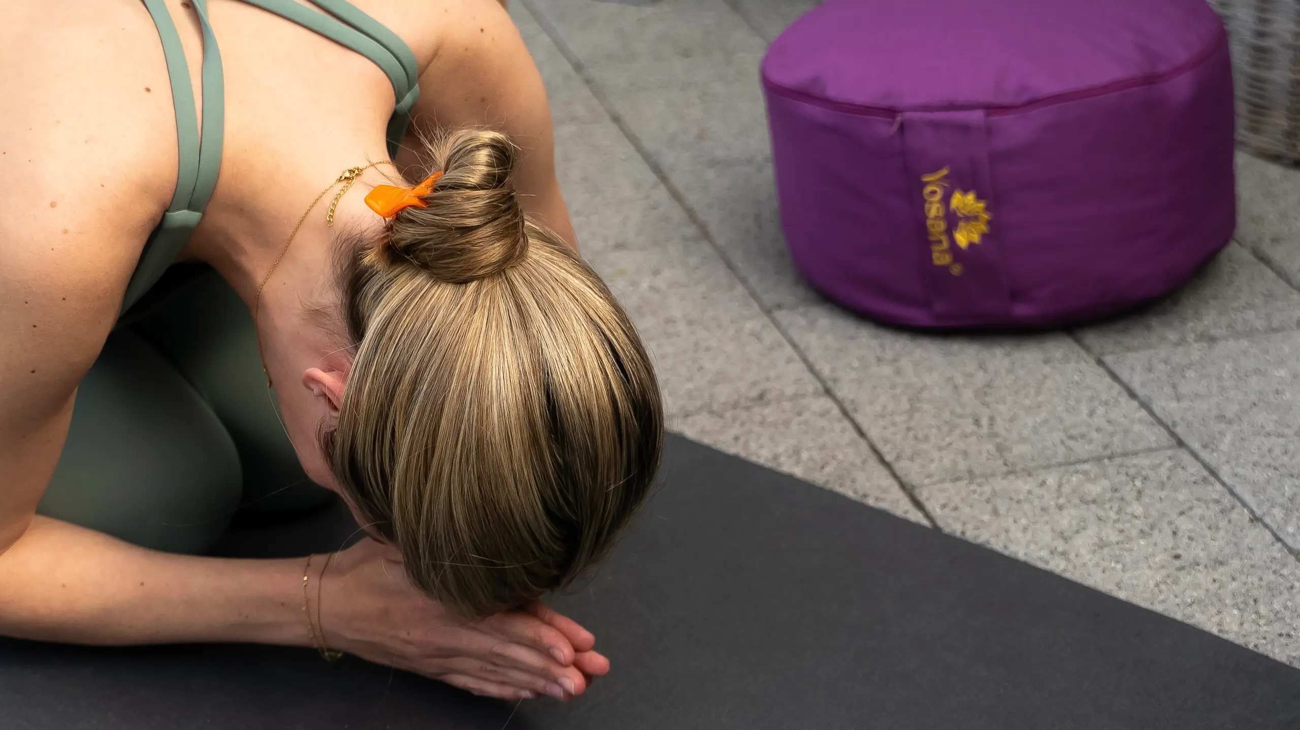 Eine Frau kniet auf einer Yogamatte und hat ihren Kopf bis zur Matte gebeugt