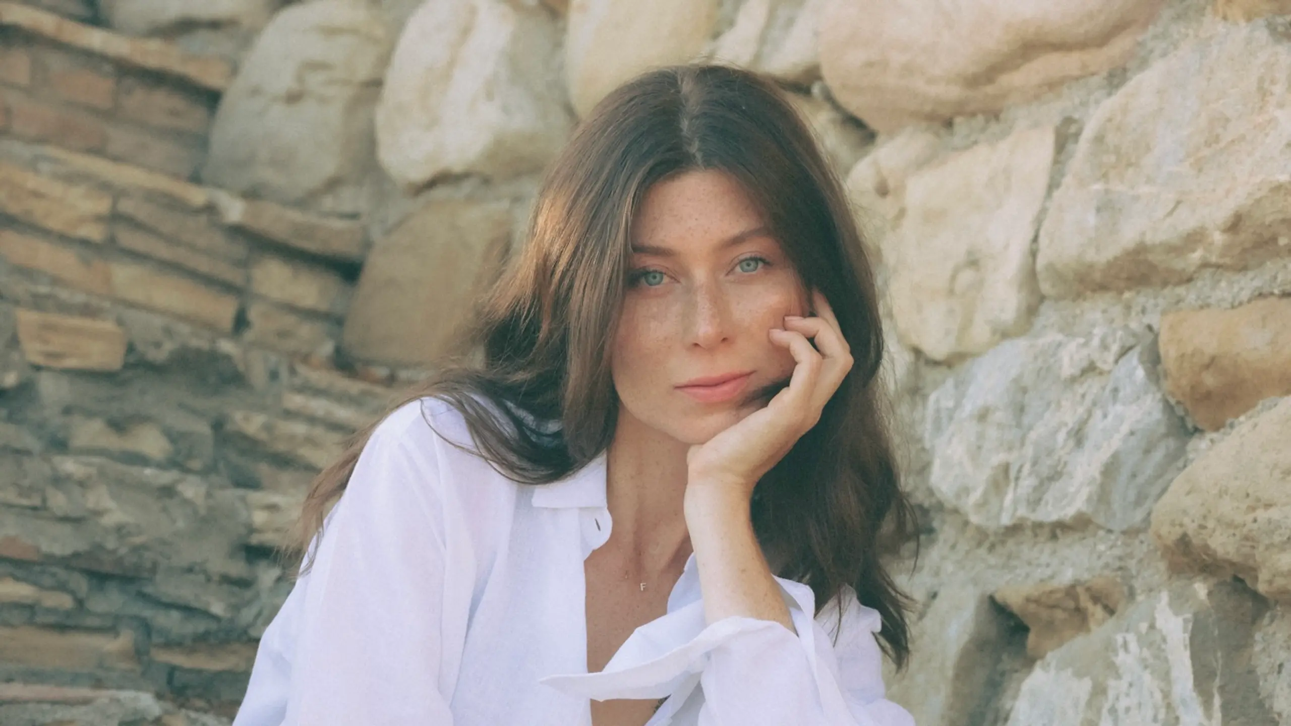 eine Frau träckt eine weiße Bluse und eine weiße Hose, sie hockt