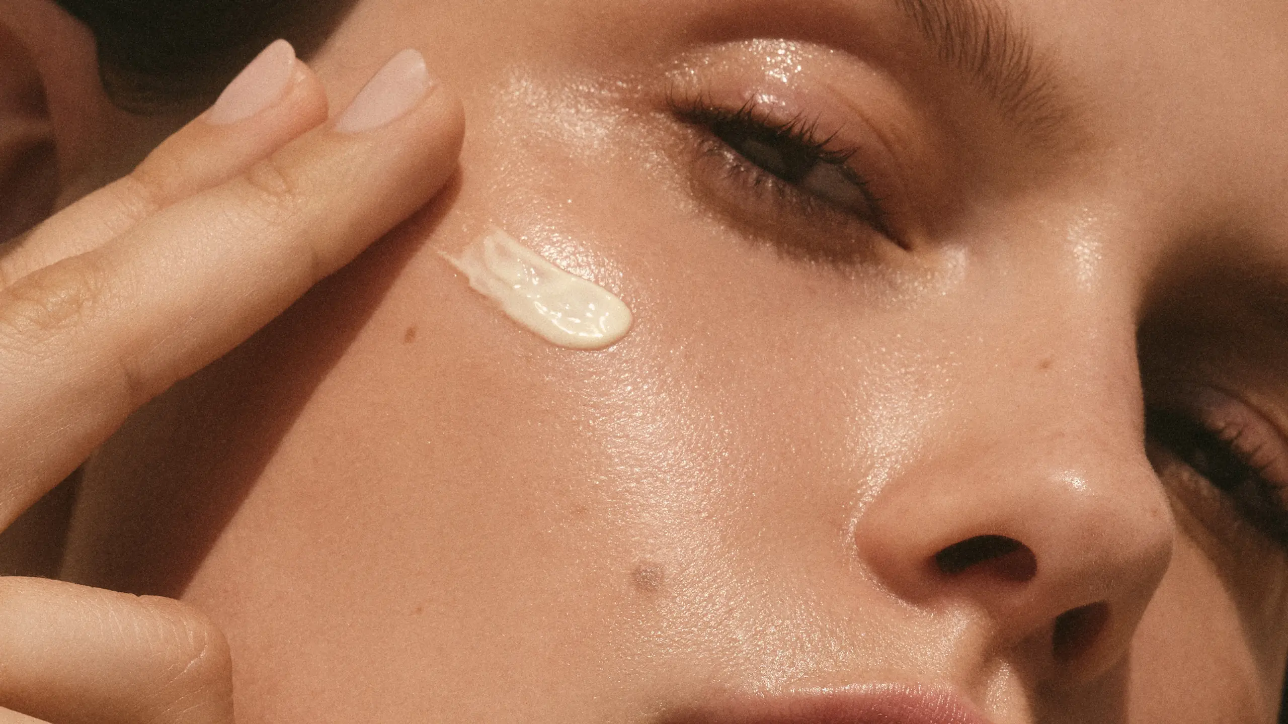 Nahaufnahme von einem Gesicht einer Frau, sie hat Creme auf der Wange