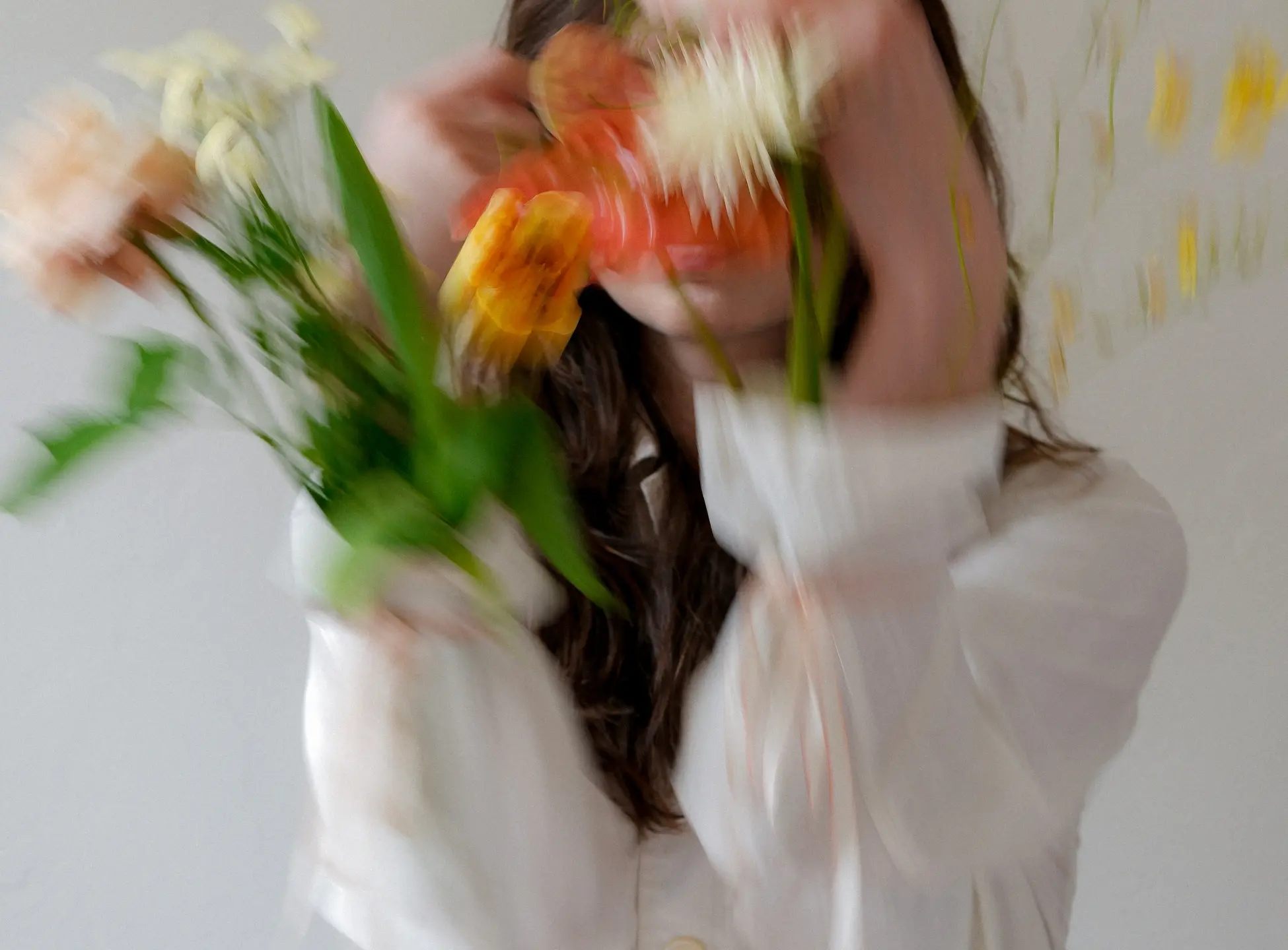 eine Frau in weißem Hemd, sie hat Blumen in den Ärmeln, das Bild ist unscharf