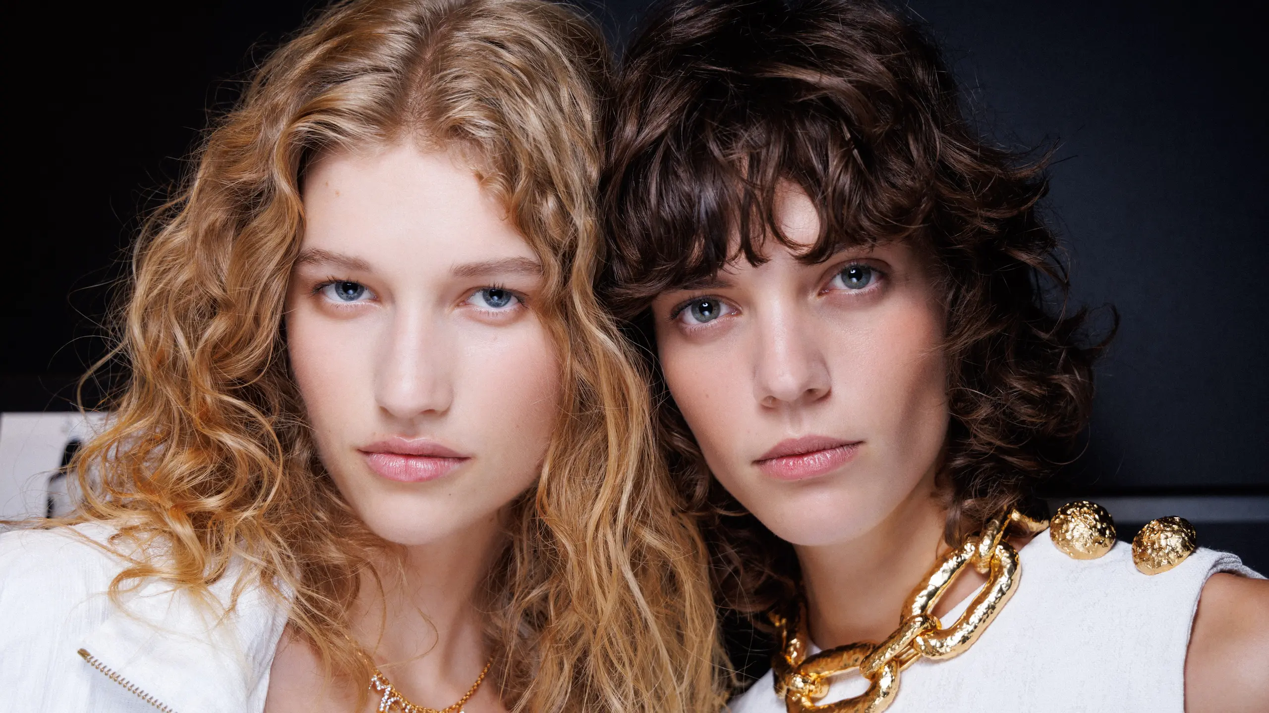 Linkes Model mit langen lockig blonden Haare und rechtes Model mit kürzeren braunen Haaren, beide in weiß gekleidet