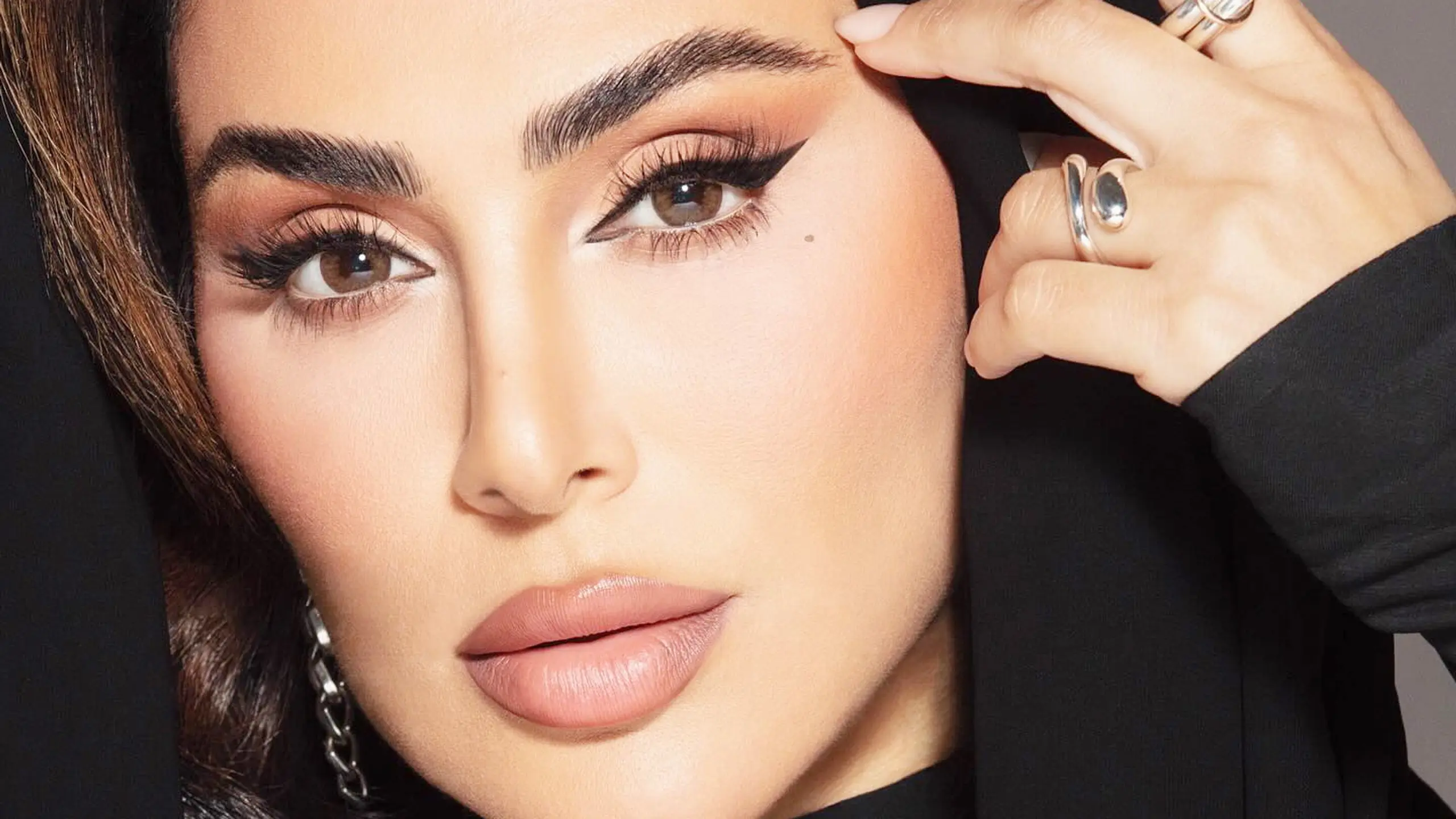 Porträt von Huda Kattan mit ebenmäßig mattem Teint, matten Nude Lippen und großem Eyeliner