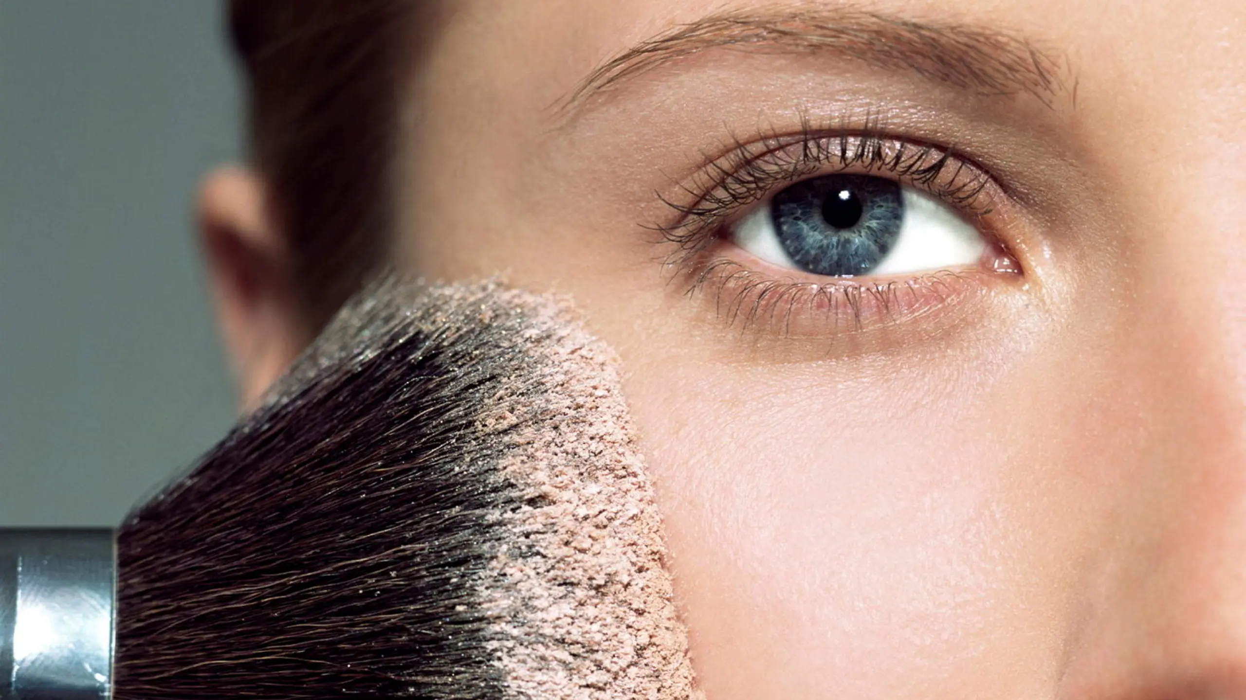 Close-Up Frau mit Puderpinsel auf der Wange