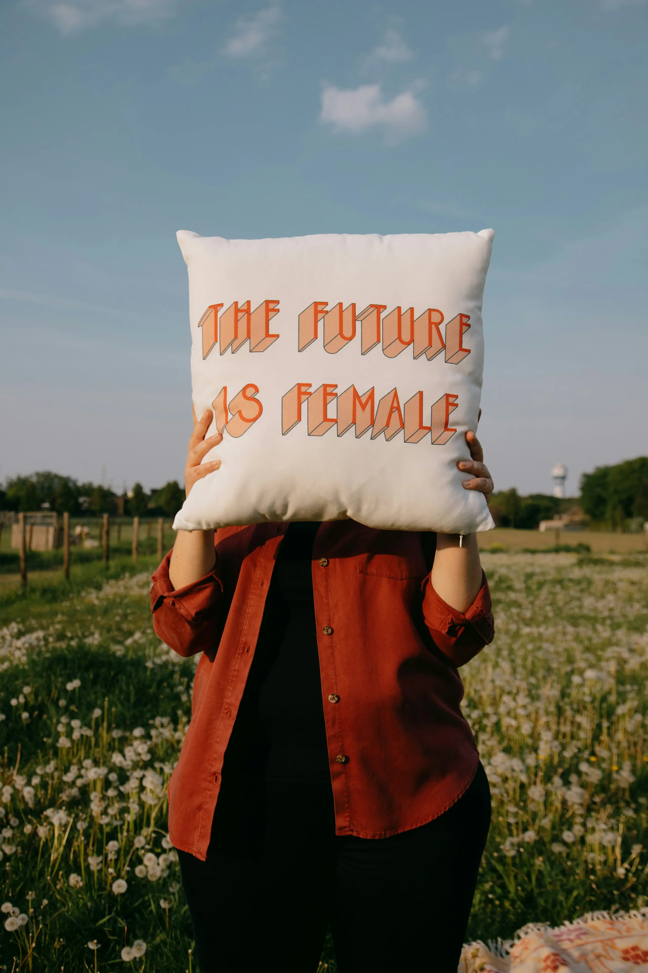 Eine Frau hält ein Kissen hoch, auf dem steht "the future is female"