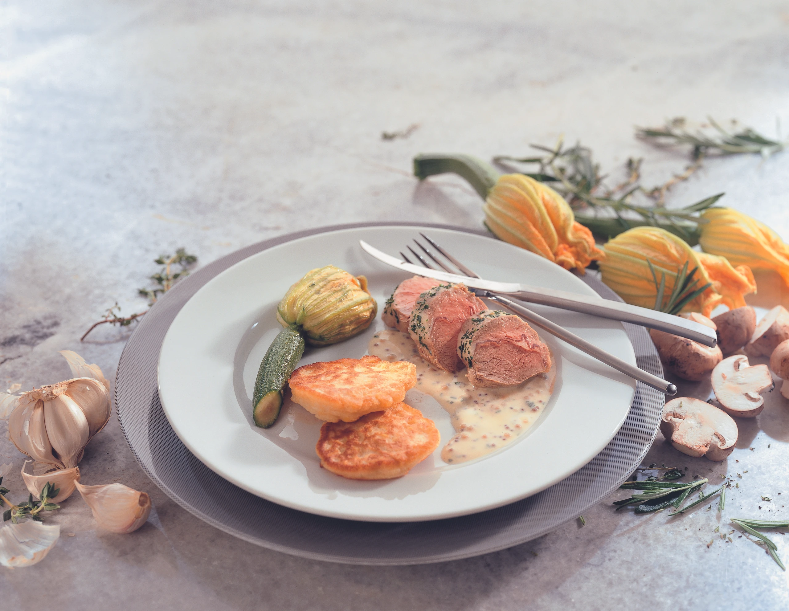 Pochiertes Lammrückenfilet mit Maisblinis und gefüllten Zucchiniblüten