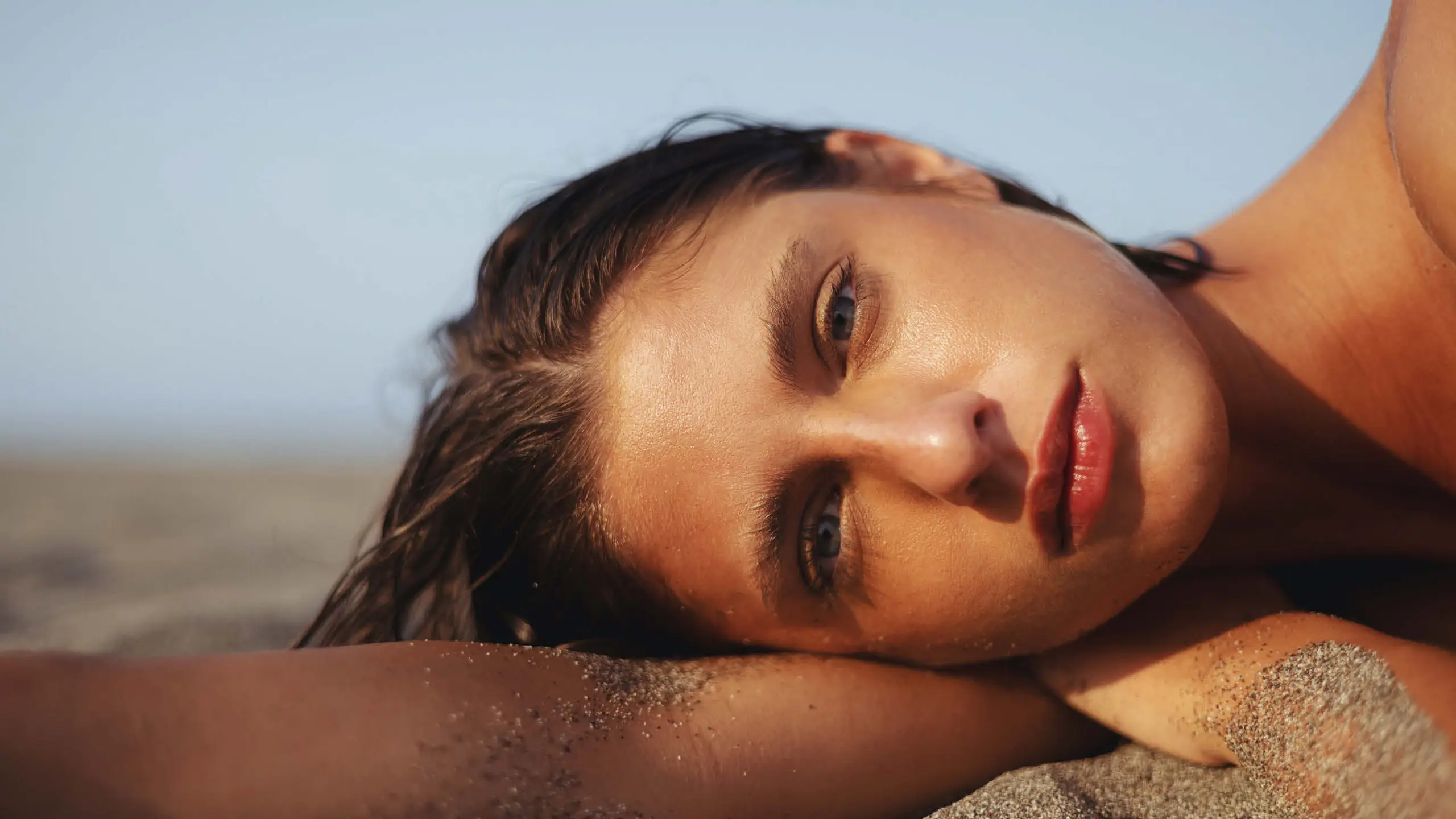 Frau liegt seitwärts im Sand