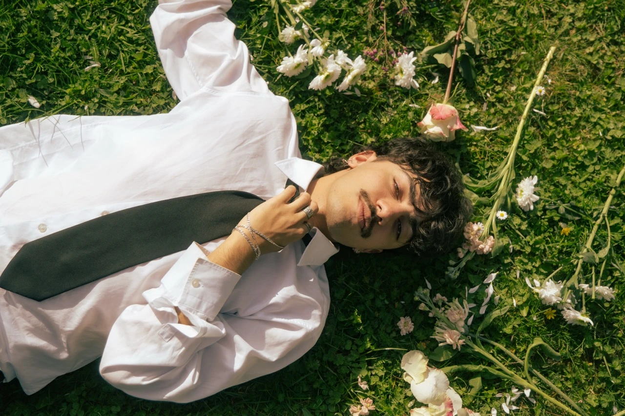 © Fey Wilbrandt Entspannter Mann in weißem Hemd und Krawatte liegt auf blühender Wiese.