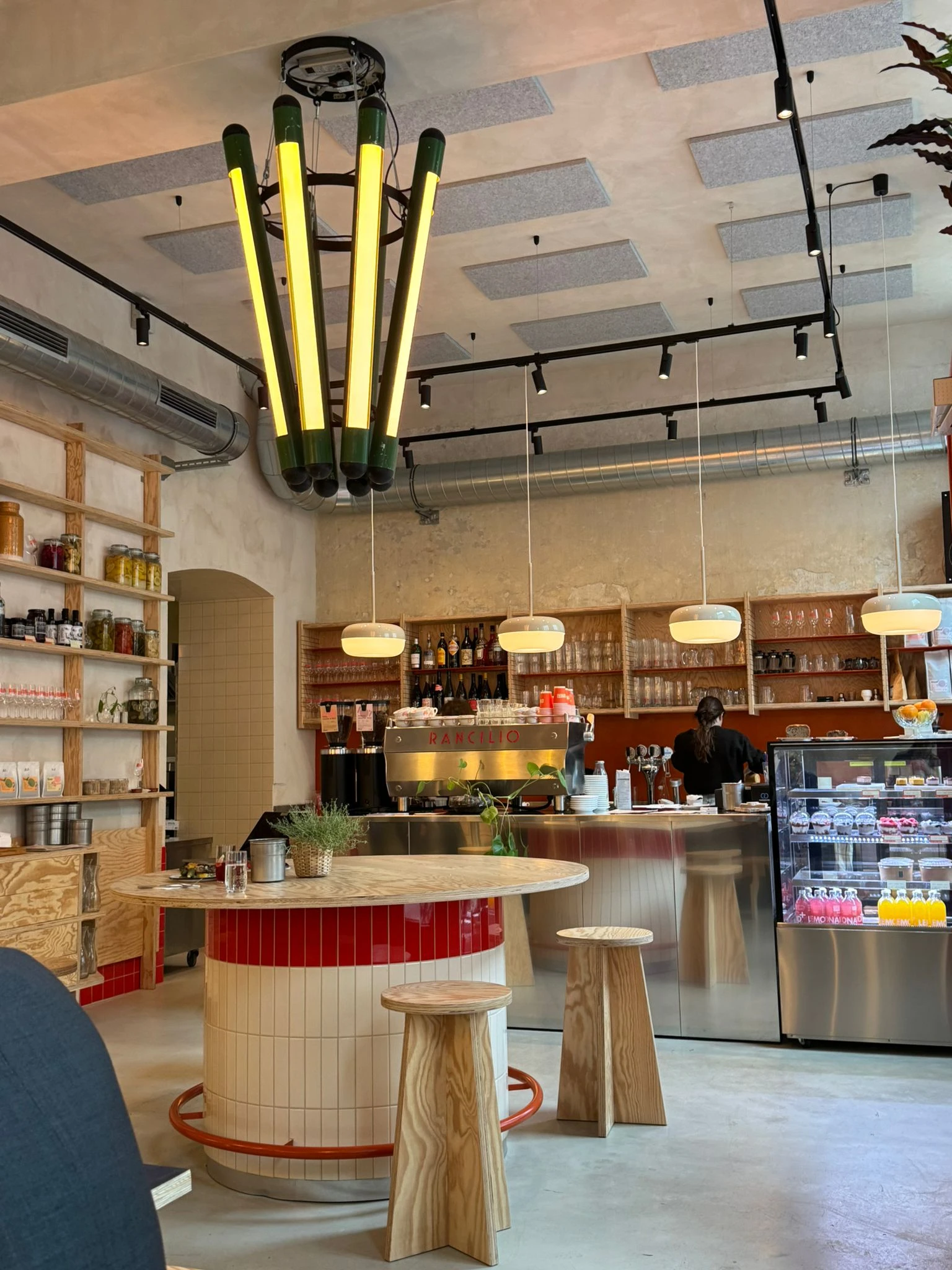 Café-Interieur mit Theke, Regalen und Beleuchtung.